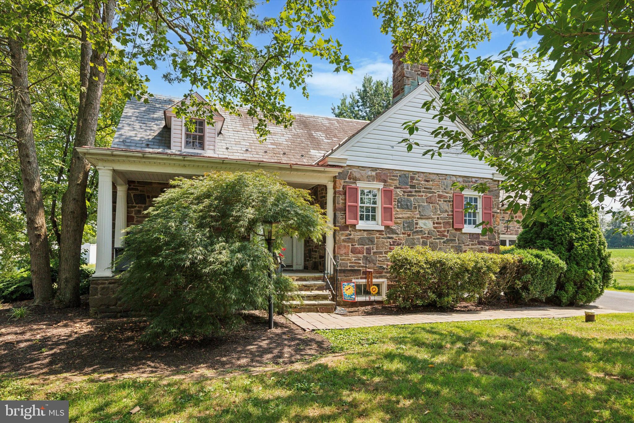 Tucked away on over 6 acres in scenic Bedminster Township, this Colonial home blends rustic charm with timeless craftsmanship in a peaceful, country setting yet remains just minutes from modern conveniences! From the moment you arrive, the curb appeal impresses with a beautiful stone façade, covered front porch, and an oversized two-car garage with additional parking in the wide driveway. Step inside to rich hardwood floors and a thoughtfully designed layout. One side of the main level features a spacious family room with exposed beams, which flows seamlessly into a dedicated dining area with custom built-in shelving. On the other side, a cozy living room showcases a wood-burning fireplace with a striking stone accent wall. The kitchen features plenty of cabinetry, stainless steel appliances, a charming brick accent wall, space for a dining table, and direct access to both a practical mudroom and the rear deck, perfect for seamless indoor/outdoor living and entertaining. Completing the main level is a convenient powder room. Upstairs, the spacious primary suite features wall-to-wall carpeting, built-in closets, and an ensuite bathroom with a vanity and tub-shower combo. Two additional well-sized bedrooms offer ceiling fans and generous closet space, and share access to a large hall bathroom with a dual vanity, stall shower, and separate soaking tub. A bonus room on this level adds flexibility, perfect for a home office, guest room, or creative space. The walk-out lower level expands your living area with a large recreation room, wet bar, and leads directly to a stone patio ideal for grilling or lounging. Outdoor lovers will appreciate the multiple outdoor living areas, expansive backyard, and tranquil pastoral views. Whether you're enjoying your morning coffee on the deck or hosting friends on the patio, the setting is nothing short of serene. The property’s zoning and proximity to nearby commercial spaces open up rare possibilities for live/work flexibility. Located just minutes from downtown Dublin Borough and major routes like Route 313 and Route 611, you’ll enjoy easy access to shopping, dining, and everything Greater Bucks County has to offer, all while savoring the space and privacy of your own personal retreat. Don’t miss out, schedule an appointment today!