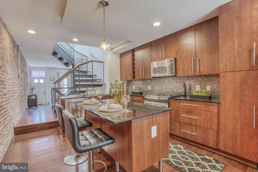 City Chic Living at an Affordable Price - This home was completely remodeled in 2007 and designed to be unique, stylish and energy efficient.    Buyers will appreciate the wood floors, exposed brick, recessed lighting & open light filled staircase.  The gourmet kitchen offers granite counters, stainless steel appliances,  gas range and island.  The bedrooms are just as unique as the main level, but the bath will steal the show.  A double door entry opens to a spa like bath complete with soaking tub, large vanity, separate shower and skylight. Never fear a cold bath or shower with the tankless water heater.  The finished basement is a cozy get away with a wood pellet stove and third bedroom potential.  Parking is accessed via a gated alley and the environmentally friendly parking pad will fit up to 2 cars.  Outdoor space continues with the 2nd level deck  and the potential to add a roof-top deck in the future.  Located in the vibrant neighborhood of Patterson Park this home  will not disappoint.