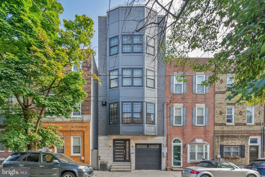 A truly bespoke home built as a personal residence by one of the city's most exacting developers, 312 Monroe St is a shining example of luxury living, boasting modern finishes, thoughtful details, and sought-after amenities. This 4-story property offers 4 bedrooms, 3.5 bathrooms, a 1-car garage, a finished basement, a private patio, a roof deck, and a coveted Queen Village location in the top-rated Meredith School catchment. A quiet, tree-lined block leads to the towering front facade showcasing the extra-wide lot. The distinctive entry door ushers you to a foyer with two coat closets. Hardwood floors extend down the hall past the garage to a private office fitted with a built-in corner desk for two and an attached full bathroom. Through a pair of sliding doors, the secluded backyard acts as an escape from the city's hustle, perfect for barbecues, al-fresco dining, and relaxing with a glass of wine. Ascending the home's wrought-iron trimmed center staircase, you'll discover an open and airy main level with tons of space to be a gathering hub. Natural light pours into the living room from a wall of picturesque bay windows, while a tile fireplace adds warmth. The show-stopping gourmet kitchen mirrors the pages of an architectural magazine with custom shaker cabinetry, top-of-the-line Wolf and Sub-Zero stainless steel appliances, gleaming marble counters that extend up the backsplash, and a two-tiered waterfall island with seating. Completing the level is a dining area overlooking a Juliet balcony. There's more living space and a half bathroom in the finished basement, perfect for a gym, playroom, or guest suite. Up on the third level, bright spacious bedrooms with custom closets sit on opposite ends. At the center is a sleek bathroom with a double vanity and a water closet, along with a fully outfitted laundry room that takes the chore out of washing and drying. The fourth level is dedicated to the primary suite. There's a huge bedroom with more bay windows, two luxurious walk-in closets with space to share, and a spa-like ensuite bathroom adorned with a double vanity, a soaking tub, a triple-head shower, and a water closet. Topping off the home is a wet bar and wine fridge that serves the expansive roof deck where you can host friends and family on game day while watching the big screen with the city skyline in the background. 312 Monroe St's utilities include central a/c, gas heat, and electric hot water. In addition to everything inside, this fantastic location earns a Walk Score of 98! Lively South St is less than two blocks away, lined with an eclectic mix of popular restaurants, shops, and entertainment, while nearby Head House Square has a farmer's market and community events. Mario Lanza Park and Weccacoe Playground are also close. Target, GIANT, Home Depot, and IKEA are a short ride, plus there's easy access to Washington Ave, Columbus Blvd I-95, and South Jersey. Schedule your tour today! Owner believes that the property is close to 3500 ft.²