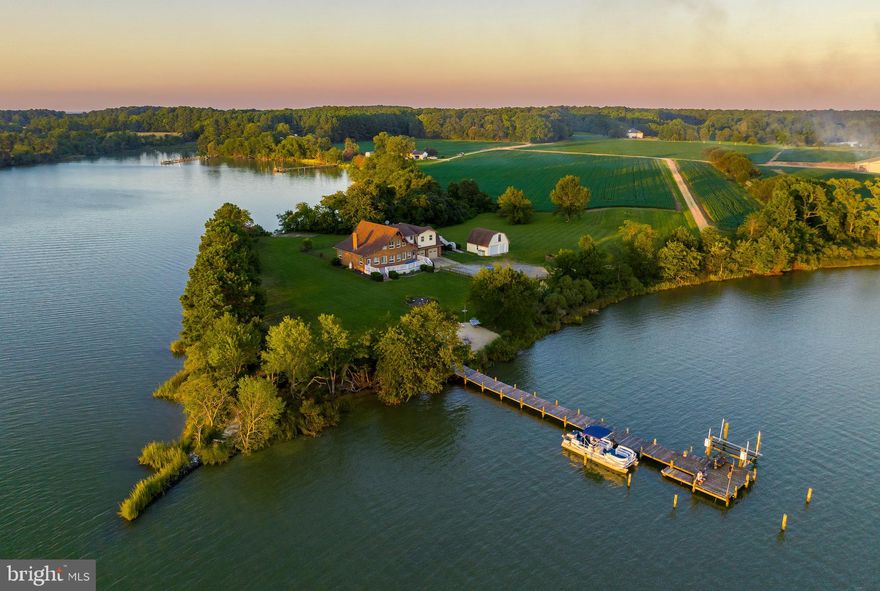 Discover a truly remarkable and picturesque 15.49-acre waterfront farm nestled on a serene peninsula along Saint Jerome’s Creek. 
Boasting approximately 1,345 feet of pristine water frontage, this unique property offers a private dock and boatlift, along with a rare, irreplaceable concrete boat ramp—a feature you could never replicate today due to current regulations.
The main house features three spacious bedrooms, full kitchen, family room, butlers pantry and three full baths while the in-law suite above the attached two-car garage adds two more bedrooms, a family room, full kitchen and full bath making it a total of five bedrooms and four full baths. Perfect for extended family or guests.
This property is not only a personal retreat but also an income-generating vacation rental, offering the opportunity to earn income while you are not there to enjoy it yourself. 
Actively being farmed, it presents an array of outdoor activities, including fishing, lounging by the fire pit on the beach, or taking a dip in the in-ground concrete pool. The expansive front and rear decks provide the perfect spaces to soak in the breathtaking views.
In addition to the attached garage, there is also a detached garage with ample storage above, ensuring you have all the space you need for your equipment and toys.
This one-of-a-kind waterfront farm offers a unique blend of tranquility, recreation, and income potential, making it a rare find that you won’t want to miss.