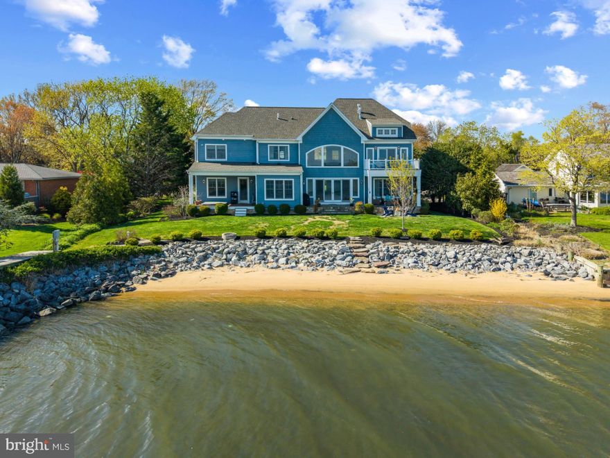 Coastal-style waterfront home with beach, pier and breathtaking open water views of the South River stretching all the way out to the Chesapeake Bay. Designed with an open floor plan and an abundance of natural light, this home features soaring ceilings in the living room and a dramatic floor-to-ceiling stone fireplace that anchors the space. The family room, with its elegant coffered ceiling, and the adjacent dining room both offer sweeping water views, creating the perfect setting for everyday living and entertaining. The gourmet kitchen is a chef’s dream, complete with a large center island with seating, top-of-the-line appliances, and an oversized walk-in pantry. A spacious laundry/mudroom with utility sink adds convenience and function. Also on the main level is a well-appointed guest suite with a private ensuite bath—ideal for visitors, extended family, or multigenerational living. Thoughtfully located away from the main living areas, it offers both comfort and privacy for overnight guests. Whether hosting weekend visitors or accommodating one level living, this main-level suite provides a convenient and flexible living option. Upstairs, the luxurious primary suite is a private retreat featuring vaulted ceilings, a cozy fireplace, a private waterfront balcony, and a spa-inspired bath. Three more bedrooms and two full baths including an additional ensuite bedroom provides plenty of space for family and friends. The waterside of the home is designed for ultimate outdoor living with a covered deck equipped with a TV, dining area, firepit, and an in-ground hot tub located just outside the guest suite. The ideal spots to end or begin a fabulous day of waterfront living everyday! The newly built pier with multiple slips and boat lift extends out into the South River providing easy access for a quick cruise around the river or head out for days on the Chesapeake Bay. A two-car garage with additional storage space completes this exceptional property. Coveted Hillsmere Estates community offers a plethora of amenities including a community pool, beach with pavilion, playground and picnic area. Enjoy close proximity to public/private schools, restaurants/shopping and Quiet Waters Park with over 300 acres of beautiful parkland featuring trails winding through forests and grasslands, summer concerts and winter ice skating; year-round activities are always readily available. Conveniently located to access Downtown Annapolis, head over the Bay Bridge to the Eastern shore or jump on Rt. 50 to get back to Washington, D.C. Welcome Home!