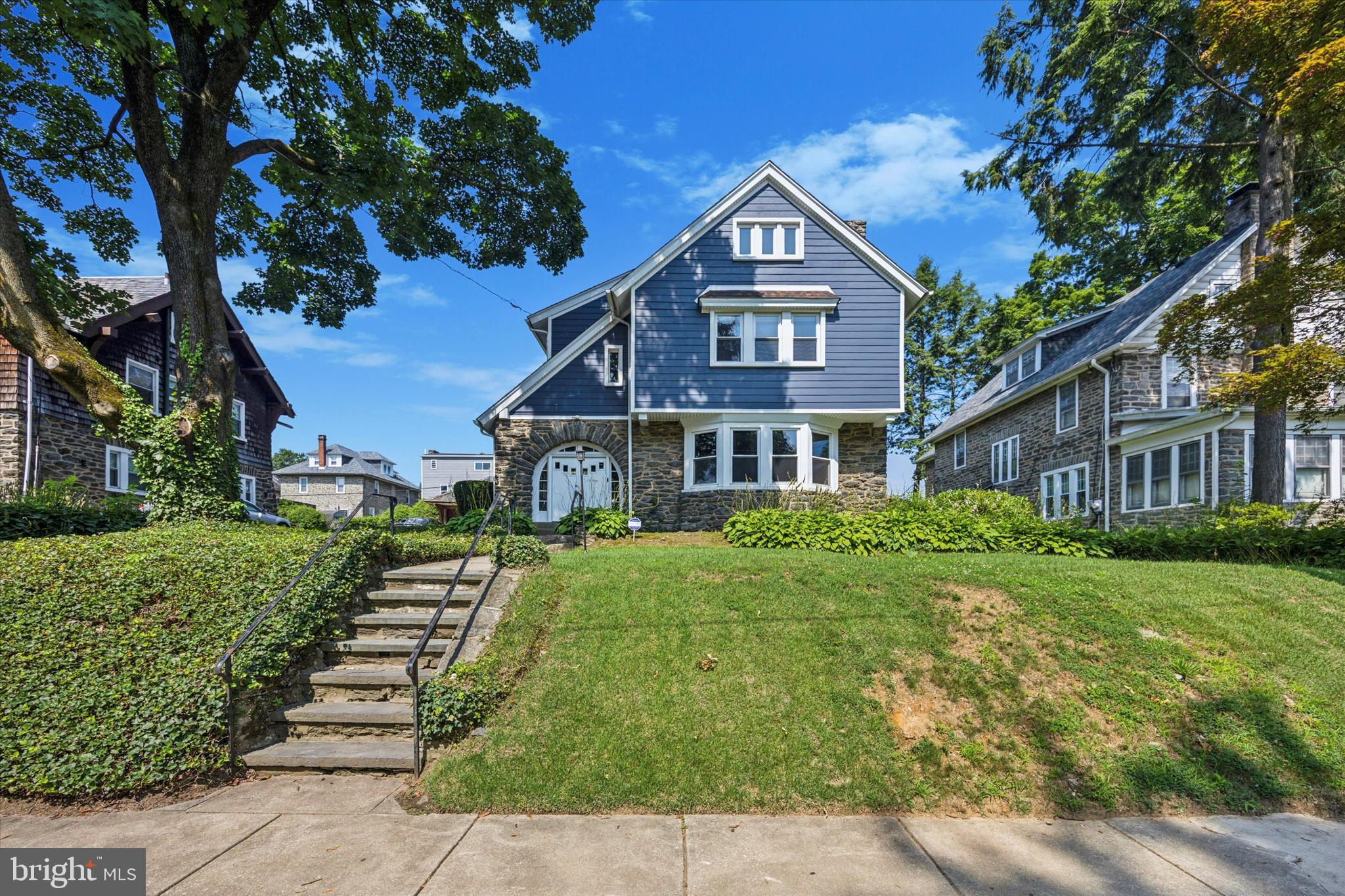 This beautifully maintained 6 bedroom, 2.5 bath Craftsman-style stone home is located on a picturesque, tree-lined street in Oak Lane. It offers approximately 3,700 square feet of living space filled with character and modern updates. Original architectural details, rich hardwood floors, and thoughtfully landscaped grounds with a large deck create the perfect blend of historic charm and comfortable living. Many new windows and low-maintenance Hardie board siding enhance the home’s exterior appeal and efficiency.
Step into an enclosed front porch with functioning windows, tiled flooring, and arched stone entryways. From there, enter the main level, where you’ll find a spacious living room with a bay window, recessed lighting, and a gas fireplace framed by an elegant stone and wood mantle. A stunning formal dining room sits adjacent to the eat-in kitchen, which features a farmhouse sink, gas stove, dishwasher, and a generous walk-in pantry. Don't miss the additional built ins for storage in the hallway to the basement. A convenient half bath, laundry room, and additional pantry space complete this level.
Upstairs, the second floor offers three spacious bedrooms and a hall bath, including an XL primary suite with a walk-in closet and private ensuite bath. The third floor includes three additional bedrooms. A finished basement with a built-in vintage bar expands your living and entertaining options.
This home has been carefully maintained with significant updates. There is a private parking spot behind the porch which is accessed through an unofficial agreement with the neighbors.
Blending timeless craftsmanship with modern comforts, this Oak Lane gem is ready for its next chapter.
Professional photos coming 7/23, showings start 7/24. Open House Sunday from 1 - 3!