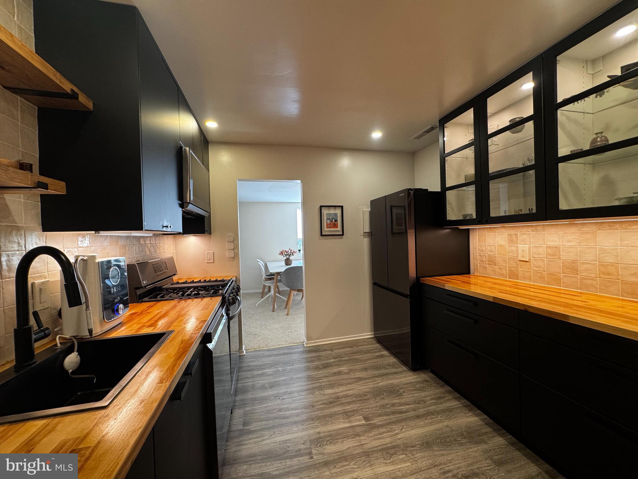 Nestled in this modest and friendly village is a rare gem of a spacious one bedroom unit featuring amongst all things, a fully remodeled kitchen (2023) designed by the architect owner of the property. The contemporary kitchen with clean lines of black cabinetry contrasted by soft-edged wall tiles and a butcher block countertop, gives a warming glow. Designed for efficiency, the full-height cabinetry provides ample storage with select glass doors to highlight visual displays. The well-equipped kitchen is complete with sleek LG black stainless steel appliances with smart capability. The premium 5-burner range, including grill and griddle top and oven with air fryer function, a sleek built-in microwave w/extendable range hood, and a quiet powerful dishwasher that makes cleanup a breeze, combine to make this a gourmet chef's dream! With the dimmable LED cabinet lighting, this kitchen will make your coffee and meal prep time a true delight.
This spacious condo has been remodeled with recessed LED lighting in all rooms, enhancing the versatility of every space for different activities and moods. The bath features a new vanity and mirror cabinet. Generous built-in wall storage makes the clutter-free dream a reality. The decor brick wall gives the dining area a unique character, while the sun-drenched living room has access to the large , private balcony, providing a relaxing outdoor escape. With a full size washer and dryer just steps from the bedroom, laundry couldn't be easier!
Enjoy all the amenities that Montgomery Village has to offer in this friendly community that is close to grocery stores, restaurants, and retail, including the nearby Costco. There is abundant parking right out the front door, recent remodeling in the community, and friendly on-site management. All utilities are included in the condo fee. All this combines to make this a wonderful place to live, work, and play!