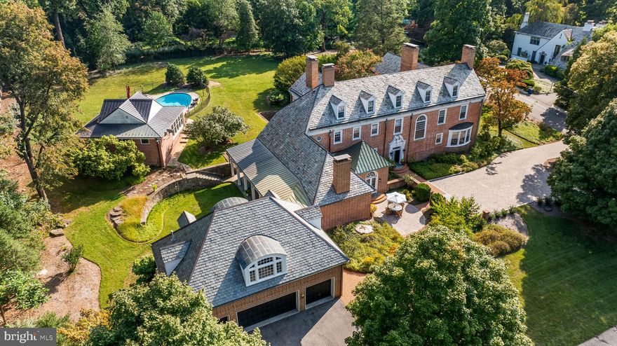 In the prestigious Blythewood community of Baltimore, 20 Blythewood Road stands with quiet grandeur, a stately 1926 Georgian home that has grown and evolved with seamless updates while retaining its classic elegance. Set on 1.58 professionally landscaped acres, this stately brick residence boasts five bedrooms, five full baths, and two half baths. Thoughtfully expanded over the years, the home exudes classic charm while incorporating contemporary conveniences, from an upgraded roof and drainage system to a fully renovated elevator. With exquisite architectural details, multiple fireplaces, and sophisticated entertaining spaces, this exceptional property can be found in one of Baltimore’s most sought-after neighborhoods. Upon entering the spacious foyer, visitors are greeted by a striking marble floor with black accents, intricate moldings, and an elegant glazed entry door. The main hall flows effortlessly into the formal living and dining rooms, both showcasing hardwood floors, raised paneling, and wood-burning fireplaces with stone surrounds. The living room’s French doors open to a serene garden, while the adjacent sunroom, wrapped in windows, provides a bright retreat with access to the lush grounds. The formal dining room offers an exquisite entertaining space, complete with easy access to the climate-controlled wine room, a connoisseur’s dream featuring custom mahogany storage and shelving. The expansive kitchen boasts extensive custom cabinetry, marble countertops, and top-of-the-line appliances, including a Sub-Zero refrigerator, Thermador gas range, and two dishwashers. A butler’s pantry with additional storage and prep space leads to the formal dining room, while the adjacent family room offers a more relaxed setting. Here, a coffered ceiling, built-in bookcases, and a stone gas fireplace create a warm and inviting atmosphere. French doors lead out to the arcade, connecting the home seamlessly with the outdoor living spaces. A wet bar and richly paneled library complete this level, providing a perfect space for entertaining or relaxation. The second floor is anchored by an luxurious primary suite, featuring a spacious bedroom with a fireplace, a private sitting room surrounded by floor-length windows, and a separate office or secondary master with its own fireplace and walk-in closet. The luxurious en-suite bath includes a steam shower, jetted soaking tub, and dual vanities with marble countertops. Three additional bedrooms, each with private or en-suite baths, offer generous accommodations, while a back hall leads to an additional guest suite, laundry facilities, and an elevator stop. The third floor presents even more possibilities, with a dedicated office, a large cedar closet, and an additional bedroom with a private bath. 
The lower level provides ample storage, a well-equipped laundry room, and a workshop space. A separate four-car garage includes a beautifully appointed studio apartment, complete with a vaulted ceiling, coffee bar, and two bedrooms, each with private baths—an ideal guest or in-law suite. Outside, the meticulously designed grounds include a sunken garden, multiple patios, and a gracefully arched arcade leading to the fenced pool terrace. The heated oval pool is complemented by a brick pool house featuring a gym, media room, and full bath.  An exquisite gem in the heart of Baltimore, 20 Blythewood Road offers an exceptional lifestyle defined by elegance, comfort, and unparalleled craftsmanship. ** Measurements, Room Count, and Bath Count include Main Residence Only***