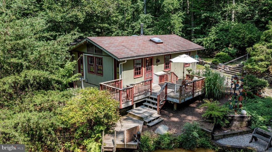 Nestled in serene Bluemont, VA, this enchanting 1-bedroom, 1-bath cabin (with detached 1 bed/1 bath studio) offers a unique blend of rustic charm and modern inspiration. Set on 7 acres with soaring trees and your very own mountain spring, the property is a peaceful haven drenched in nature, yet still within the metro area commuting threshold. For outdoor lovers it is truly a “Stones Throw” to the Appalachian Trail and a quick drive to the boat launch at the Shenandoah River. With easy access to Route 7 and Route 50, you're only 25 minutes to the towns of Middleburg and Berryville, making this an ideal retreat with convenient access to amenities. Years ago, the owners of this property envisioned a little piece of paradise that they could carve out of Paris Mountain. Today years of love and dedication poured into the property, spring to life again for lucky new owners. Here, beneath a canopy of beautiful trees, you'll discover their whimsical cabin, and a stunning Frank Lloyd Wright-inspired bunkhouse built by the owner’s own hands. The property even comes with a delightful surprise—a petite pond teeming with a few massive koi and a hearty school of fish, which will convey to the new owners!
Inside the cozy cabin, simplicity blends with rustic elegance. Soaring ceilings with wood beams and rich pine floors create a warm, inviting atmosphere. The full bath and bedroom make this an ideal or year-round residence weekend getaway. A home office easily doubles as a nursery or playroom, and the centrally located wood stove provides warmth and coziness. An abundance of windows ensures that the interior is bathed in natural light.
For your guests, the Frank Lloyd Wright-inspired bunkhouse offers a getaway retreat with a studio bedroom and a full bath. This unique structure features Wright's signature "cornerless window," designed to eliminate visual obstructions and create a seamless connection with the natural surroundings. Wright himself would have been impressed with this delightful creation.
The backyard is an oasis, an award-winning creation that once graced the pages of Garden & Design magazine and won the prestigious Golden Trowel Award in 2005. The garden is a carefully curated mix of perennials, including hostas, ferns, yews, lush grasses and a stunning Japanese Maple.  Stone walls and gravel paths blend seamlessly with the natural landscape, creating a harmonious feel. Shady nooks, cool water, and a sunny spot for a tomato garden are all here. It sounds impressive and it is! But amateur or beginner gardeners don't be scared away- the garden was designed and installed surprisingly by an amateur and it is designed to be enjoyed more than toiled over.   
The eye-catching metal sculpture in the heart of the rear yard with cascading geometric shapes and year-round color adds a touch of artistry and will remain as a gift from the sellers to the new owners.
Whether you are relaxing on the deck or grilling “pond side” in the gravel patio area flanked by the stone wall, you hear the soothing sounds of native birds, the rustling of animals across the forest floor, and the gentle splash of water from the mountain spring into an earthen pot.
For everyday maintenance there is a “barn/shop” to do woodworking or other garden hobbies with a handy access door for your ride on lawn mower.
This property is more than just a home; it's a lifestyle, a sanctuary, and a piece of art.  Henry David Thoreau, famously said in Walden: Or Life in the Woods.  "I have learned, that if one advances confidently in the direction of his dreams, and endeavors to live the life he has imagined, he will meet with success unexpected in common hours." Who knows what magic life in the woods will bring to you?
