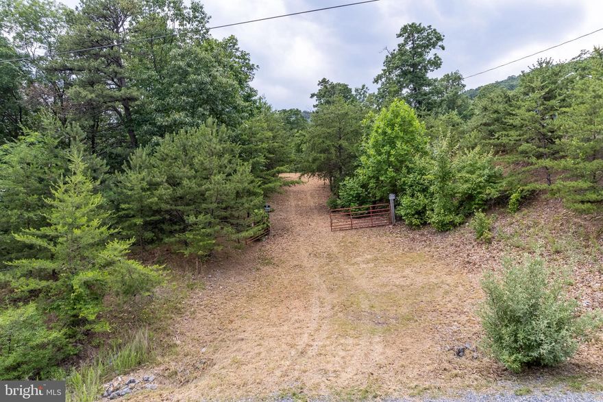 Build your dream home or vacation getaway in the quiet mountain subdivision of Crescent Orchards. 7.26 acre lot gives the illusion of being in the middle of nowhere while being just 20 minutes from Winchester. Landscape is mountainous with rolling hills. A natural spring is on the left side of the property at the bottom of the hill. Public road makes access to gated driveway easy. The lot borders Sleepy Creek for 100 feet.  A portion of the lot has been cleared by the owners for their camper, making for a perfect weekend or vacation retreat until you are ready to build. Power line pole is located at the front of the lot making electric easily accessible. Well and septic has not yet been installed, sellers had a perc test done when purchased. Restrictions are light, but enforced. The roads are maintained by the HOA. Horses and ponies are welcome provided they are allowed a minimum of one acre per animal. No swine or poultry.