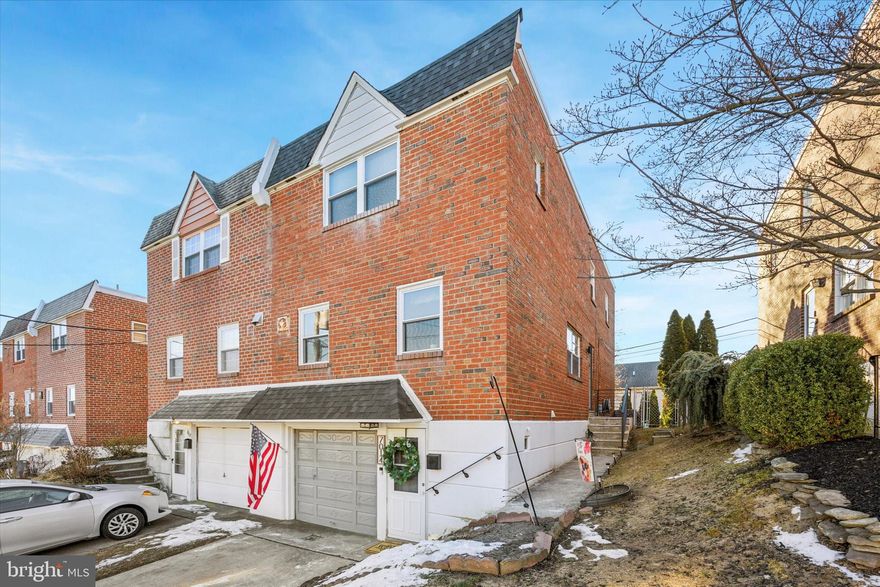 Welcome to 7014 Mathias Street, a home perfectly positioned between vibrant  Manayunk and the outdoor haven of Wissahickon Park, offering the best of both worlds — city living and nature at your doorstep.

Upon entering, you’re greeted by a sun-filled, spacious living room with wide-plank flooring that’s both durable and inviting. The generous dining room provides ample space for hosting large gatherings, while the separate eat-in kitchen boasts a bright, clean aesthetic, bathed in natural light, making it a joy to cook in.

The chic powder room adds a touch of elegance with its warm color palette, chair rail, wainscoting, and stunning, contemporary wallpaper.

Moving downstairs, there’s no traditional basement here. Instead, enjoy a sunny and versatile lower level that’s perfect for a variety of uses. This space includes a laundry room, interior access to the garage, and sliding doors that open to the expansive backyard, offering a great spot for both play and relaxation.

Upstairs, black iron handrails lead the way to three spacious bedrooms - the first two filled with light and equipped with well-appointed closets. A full bathroom retains timeless charm with its original tile and full tub, adding character to the home.

The primary suite is a true retreat, offering an abundance of sunlight and plenty of space for a king-sized bed. Its newly renovated bathroom features modern, stylish finishes, including a walk-in closet, a wood vanity with a stone sink, shiplap detailing, and a custom tiled shower with a glass enclosure, dual showerheads, and a luxurious rain shower.

This home also boasts a large, private backyard — a rare find, giving you a tranquil space to unwind and enjoy the outdoors.
