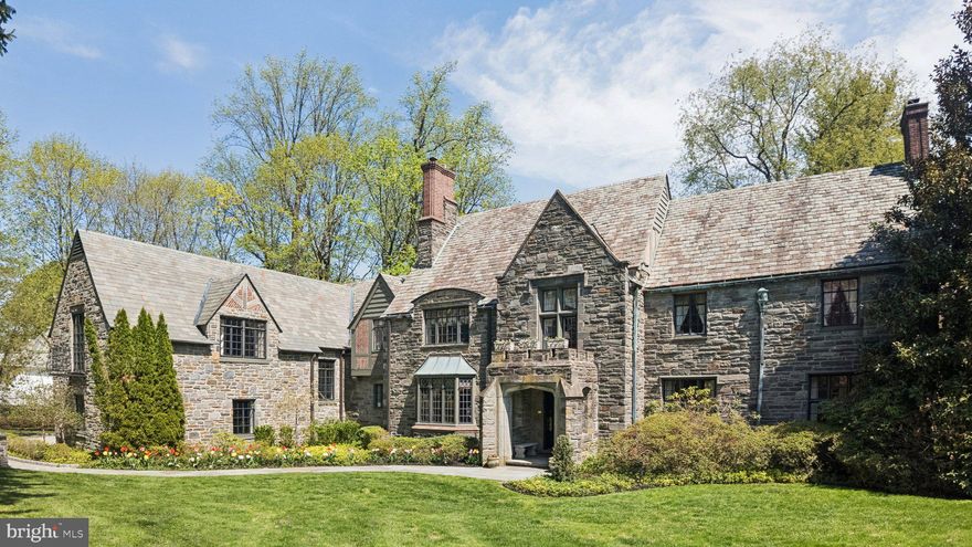 Welcome to 517 Fishers Road — a masterfully preserved Tudor estate where timeless architecture meets refined modern living, set on a lush, private acre in the coveted Northside enclave of Bryn Mawr. From the moment you arrive, the home evokes the quiet grandeur of a bygone era, reimagined for today's most discerning buyer.
The art of living begins in the gracious entry foyer, where rich hardwood floors set the tone for the elegance that unfolds throughout. A formal living room anchored by an ornamental fireplace invites intimate gatherings, while an adjacent sun-drenched reading room — lined with custom built-ins — offers a serene escape for quiet reflection.
A richly paneled executive office, distinguished by stately stonework and an atmosphere of cultivated sophistication, serves as the ideal private retreat for those who work as beautifully as they live.
As evening falls, the magnificent dining room becomes the undisputed centerpiece of the home — a stage for unforgettable entertaining, presided over by a glittering Baccarat chandelier that casts the room in pure glamour. Just beyond lies the true heart of the residence: a chef's kitchen that masterfully balances modern performance with timeless style. Outfitted with dual ovens, a custom-paneled refrigerator, Miele induction cooktops, and bespoke butcher block counters, this is a space where everyday moments feel like occasions. The kitchen flows effortlessly into a sun-drenched sunken living room with soaring coffered ceilings and a breathtaking Delft-tiled fireplace — a wall of windows framing the private stone patio beyond. Two elegantly appointed powder rooms complete the main level's seamless design for elevated entertaining.
The upper levels are home to five spacious and luminous bedroom suites, each a bright and private sanctuary. The primary suite is a world apart — a true retreat featuring a spa-inspired ensuite with a deep soaking tub, a beautifully tiled walk-in shower, and a generous walk-in closet. A half-flight above, an additional bedroom and a versatile bonus room with vaulted, beamed ceilings offer an elevated sense of seclusion and possibility.
Above it all, the attic level presents a remarkable opportunity: a fully realized fitness studio alongside generous storage and a cedar-lined closet — a rare and welcome luxury.
Descending to the lower level, a wood-paneled billiards room evokes the atmosphere of a distinguished private club, complete with a temperature-controlled wine cellar — the perfect setting for an after-dinner scotch or an evening among close friends.
Outside, the estate's grounds are nothing short of spectacular. Framed by mature, manicured landscaping and serene natural vistas, the one-acre setting feels both expansive and intimate. Dual stone patios create idyllic spaces for al fresco dining and unhurried relaxation, while a tranquil water feature lends a sense of peaceful seclusion rarely found so close to the vibrancy of the Main Line.
Completing the offering: a whole-home generator and a sophisticated security system ensure that life here is as effortless as it is extraordinary.
Situated within the top-ranked Lower Merion School District and moments from elite private schools, world-class dining, and the cultural riches of Center City Philadelphia, 517 Fishers Road is that rarest of offerings — a home of historic soul and contemporary grace, in a setting that simply cannot be replicated.