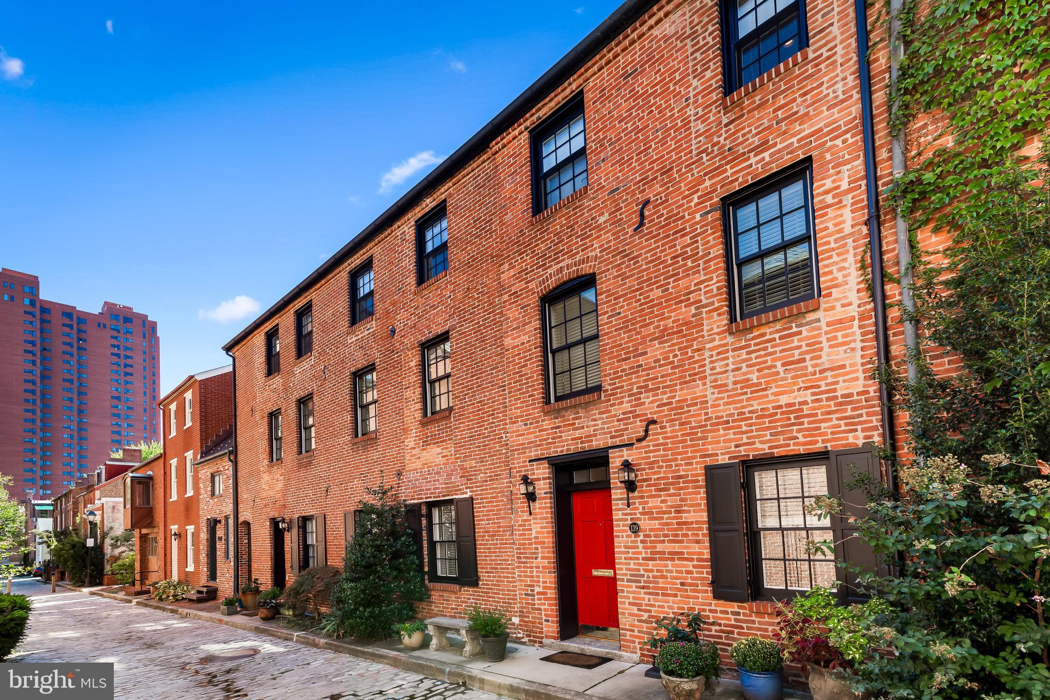 Say hello to 139 Welcome Alley, the showplace home on one of Baltimore’s most welcoming streets! Meander past the neighborhood pocket park and down this quiet pedestrian friendly 1800’s cobblestone block to this one-of-a-kind 2 bedroom, 1.5 bath townhome that is full of interesting surprises. The main level features a living room, dining room with wood-burning fireplace and a light-filled kitchen with many recent upgrades including stainless appliances, granite counters and ceiling-height cabinetry.
On the second floor you’ll find one of the bedrooms along with a cozy den and a wonderful separate family room featuring another wood-burning fireplace, built-in bookshelves, and an incredible 2-story wall of windows that leads to a sweet terrace with southern exposures. You’ll feel like you’re overlooking a quaint European village.
Travel to the top level owner’s suite to enjoy the primary bedroom, a dressing area and wall of closets overlooking the family room below, and a beautiful updated bathroom. The sizable bathroom enjoys a walk-in shower with glass doors and marble tile along with a separate jetted soaking tub. The convenience level is high as a side-by-side washer and dryer are neatly tucked into a laundry closet.
There are salvaged hardwood floors, exposed brick, and many historical details throughout. An unfinished basement serves for helpful storage. This home has been meticulously maintained and offers many significant updates, including but not limited to a replaced roof and skylight (2014), water heater (2016) and high efficiency HVAC (2021). The majority of the windows have been replaced between 2011 through 2022 as well! Otterbein is full of many hidden landscaped parks, private security, and is away from the bustle of Federal Hill and the Inner Harbor, but close enough to walk to its many popular attractions. Permit-only parking is easy here, and you are walking distance to M&T Bank Stadium, Camden Yards, the MARC train, the Light Rail and close to all major commuter routes including I-95 and 295.