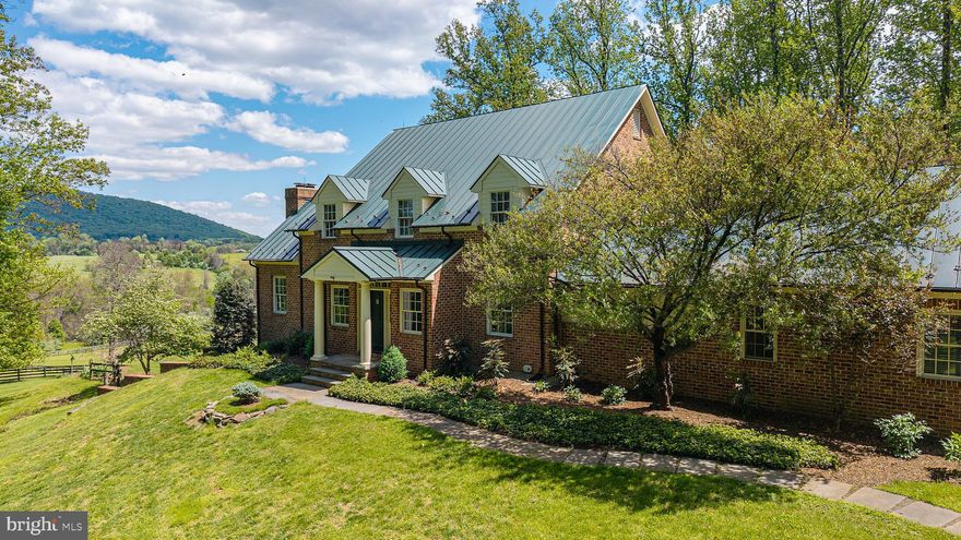 Tucked away at the end of a quiet private drive, this exceptional 21.51-acre property offers a rare blend of natural beauty and refined living. Enjoy sweeping, unobstructed views of Big Cobbler Mountain as you overlook thousands of acres protected by conservation easement—ensuring your vista remains forever unspoiled. A gentle stream meanders through the land, feeding into Thumb Run along the eastern boundary, while portions of the acreage benefit from land-use status for seasonal cattle grazing. The property is two separate tax parcels, offering flexibility and long-term value.
This elegant three-level Hunt Country style  residence offers timeless craftsmanship and modern comfort. Features include four spacious bedrooms and four-and-a-half baths, with approximately 3,800 square feet across the main and upper levels, plus an additional 1,500 square feet of beautifully finished walk-out basement space. French doors in the primary suite and dining room open to beautiful gardens. 
Exquisite custom detailing throughout, including oversized crown moldings, finely crafted window and door casings, and impressive 8-inch baseboards—hallmarks of true quality construction.
The home’s exterior showcases antique brick paired with durable fiber cement siding, complemented by a standing seam metal roof. Copper half-round gutters with leaf filters add both elegance and functionality. High-performance Pella windows and doors, along with 2x6 exterior wall construction, enhance energy efficiency year-round. Board fenced paddock and fields  with automatic waterers. 
Also included is additional detached garage building with workshop and loft, with plenty of room for equipment storage, firewood storage, together with two additional sheds. 
Welcome to a rare blend of refined living and thoughtfully designed outdoor spaces — where comfort, craftsmanship, and functionality come together in perfect balance.