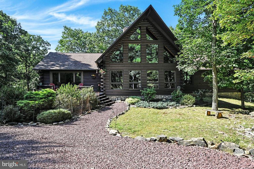 THIS is the one you have been waiting for!! Serenity & Splendor at one address!! A retreat for all seasons to celebrate & enjoy life!!  Nature Lover's Delight! Personal Paradise! Vacation Getaway! Snowbird Summer Stay! Options are yours!! This serene & pristine beauty snuggled on 1.8 acres in a private community offers an instant invitation to escape the hustle & bustle power grid of life!  This timeless contemporary log home with modern amenities  & gracious formality is situated 160' from the road overlooks a breathtaking green area  & radiates tranquility and a calming ambiance that offers a welcome invitation to unwind.  The log exterior blends harmoniously into the natural surroundings. A circular driveway welcomes you home & offers plenty of parking for family & guests. A two-tiered deck & welcoming front door ( a house warming gift from the late great actress Mary Tyler Moore & her husband Robert) greets you! A two story entry creates an impressive introduction  to this architecturally blessed home  with a harvest of features. The soaring chalet-style great room features a vaulted ceiling, beams, a wall of thermal pane windows to watch the artwork of nature change with the seasons. A 5x9x23' field stone fireplace with rough hewn mantle & a few coins embedded in the stonework for luck anchors the great room & will have you wishing for a stay at home snow day. A sweeping staircase to the right of the fireplace ascends to the stunning18x24'raised roof loft dressed w/furnishings that remain, a stone fireplace, double balcony that overlooks the great room, & offers a private haven that could be utilized as a library, family room, office, or additional sleeping quarters. A beamed ceiling caps the dining lounge at the rear of the great room and is perfect for early morning coffee or family dining.  The 15 x 20 formal dining room perfectly embraces the union of wood & glass is ready for candlelight & wine dinners or large parties & celebrations. The 14 x 14 kitchen is beautifully acquainted with granite counters, an abundance of cabinetry including a built-in desk, and a center island snack bar that enables great interaction between guests & cooks. A laundry room & half bath add convenience to the main living area.  A center hall to the right of the great room offers a pull down for access to an 8 x 24' storage attic.  The tranquil owner's suite with ensuite bath balances escapism with everyday comfort.  Large windows allow natural light & pretty views from the 2 additional bedrooms on the main floor.  The garden level offers an 840 sq ft APARTMENT/SUITE complete with a kitchen, large & bright living rm, dining area, full bath, 2 bedrooms, a private entry with recent Anderson sliders that open onto an 8 x 22 deck complete with a swing for solace & enjoyment- great for extended family or guests. A 20x20 twin door garage, utility room, workshop, storage room and a 15 x24 game room complete the lower level. A 76 foot deck compliments the rear of the home & offers the perfect place to sip your favorite cocktail, dine outdoors or simply relax &  enjoy nature's beauty. A zen-like garden embraces the screened gazebo (complete with ceiling fan & outlets)  invites you to reflect  & relax. Current owner installed oil heat, new hot water tank, Mini-split units, granite counters,  Anderson slider doors & so much more! Commuter Friendly about:7 miles from Inter. 81; 138 miles from New York; 108 miles from Phila; 74 miles from Harrisburg; 60 miles from Allentown & an easy commute to Pocono attractions.  Escape the ordinary & enter the serenity of trees & flowering paths  that surround the sanctuary of your new home!  Why wish & wait when you can own this Dream Home!! Create your new traditions & memories here!!