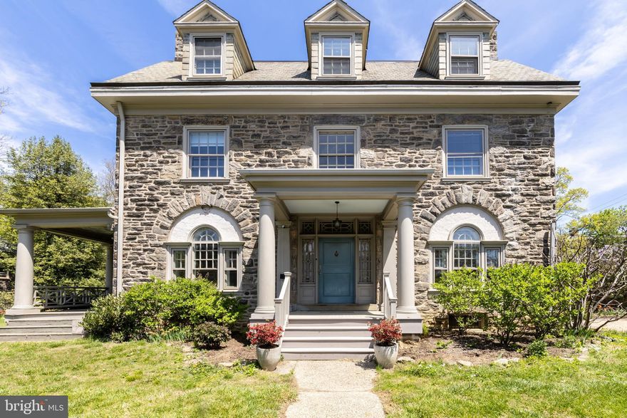 This stunning south facing corner property is your quintessential West Mount Airy home! Solidly constructed from Wissahickon schist, it's a gardener's dream! Complete with a gravel driveway and a detached garage with a guest apartment above, this half acre property was made for entertaining, with a firepit area, gravel patio for outdoor dining, and a private side porch to watch the sunset.
As you approach from the front gate, you will note the perfect symmetry of this Colonial Revival. On the first level is a generous entry hall with decorative molding, a living room with a woodburning fireplace and built in bookshelves, a parlor with a woodburning fireplace, a formal dining room with bay window, built in corner cabinet with leaded glass, and a spacious eat in kitchen with a cook's stove and bonus utility sink. A slate floored mudroom with floor to ceiling built-ins and half bath round out the first level.  Refinished quarter sawn oak floors with border inlays, three sets of original pocket doors with perfect function and hardware, decorative carved wood mantels on both fireplaces, chair rails in dining room and hallways. Wide staircase and generous landings throughout.
On the second floor you'll find the primary bedroom, with a wood burning fireplace, and a bay window with window seat.  The full bath has radiant flooring under the carrera marble tiles, an oversized walk in shower, and double sink. Two additional bedrooms are on this level. The fourth room has a woodburning fireplace, bay windows and is used as a family room, connecting to a half bath and a beautiful sleeping porch/ solarium with casement windows on 3 sides.
The third level is equipped with a dance/ yoga/ exercise room with custom wall mirrors. A full bath with soaking tub and laundry area are also on this level. Two smaller bedrooms are on this level as well as an office and a storage attic with a lovely eyebrow dormer.
The yard has mature plantings, raised bed gardens, raspberry patch, fruit trees, gravel fire pit, and gravel dining and lounging patios. It is fully fenced in to keep in little ones and pets.
The 2 car garage is a miniature of the main house, made of schist with a green slate roof. Above is a guest suite with a full bath and split system, perfect for an in-law suite or au pair!
The main house has high velocity heating and cooling with 3 zones, renovated kitchen and baths, updated electric and plumbing. Basement is full height and full footprint, with bilco doors for easy load in/ out. Take note of the steel beams in the basement that have ensured that this century old house has level floors and will never settle. Agent is owner. Showings start at Open House.