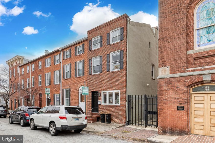 Live in the heart of Baltimore’s historic Little Italy neighborhood just steps from shops and restaurants and a 5 minute walk from Harbor East, Harbor Point, and the Inner Harbor. This extra-wide, end-unit 3 bedroom, 2.5 bath townhouse is beautifully updated, featuring exposed brick walls and architectural touches that make it both warm and a perfect home for entertaining. The main floor includes a powder room and a light-drenched, oversized sunken kitchen and cathedral ceiling over the dining area, leading to an enclosed and gated back patio which can be converted to private parking. The home sits on a gated, T-shaped, private alleyway with gates operated by remote control, ensuring privacy and frequently home to neighborhood social gatherings. The second floor features two guest bedrooms and a shared, full bathroom with an architectural-framed feature wall for art pieces. An open dark wood and black iron staircase is a key feature of the house connecting the three floors and serves as a beautiful differentiator from houses of this age. The master bedroom takes up the entire third floor, with a sitting area outside the bedroom suite and a rooftop balcony offering unobstructed views of Harbor Point, the perfect location for morning coffee or evening cocktails. The oversized master suite includes a walk-in closet customized by Chesapeake Closets and a large bathroom with steam shower and hurricane shutters on its two windows allowing natural light and privacy.  The house sits on one of the most desirable streets in Little Italy with the street well-lit by bistro string lights inviting evening walks with neighbors. Each year the house finds itself in the middle of the Little Italy Festival.  Set up a table and chairs in front of the house for a private seating area as music, food, and merriment fill Stiles Street. You will be only steps away from a number of other annual events in the neighborhood like the Italian outdoor movie nights only a block away, the annual lighting of the Little Italy Christmas tree complete with neighbors singing carols and enjoying hot chocolate, and more. This is a highly walkable area: 39 mins to M&T Bank Stadium, 30 mins to Cross Street Market, 19 mins to the Pendry, 11 mins to the National Aquarium. This location is city living at its finest, a combination of elegant and spacious interior design, highly sought after location, and easy walkability to some of the best restaurants and neighborhoods in Baltimore.