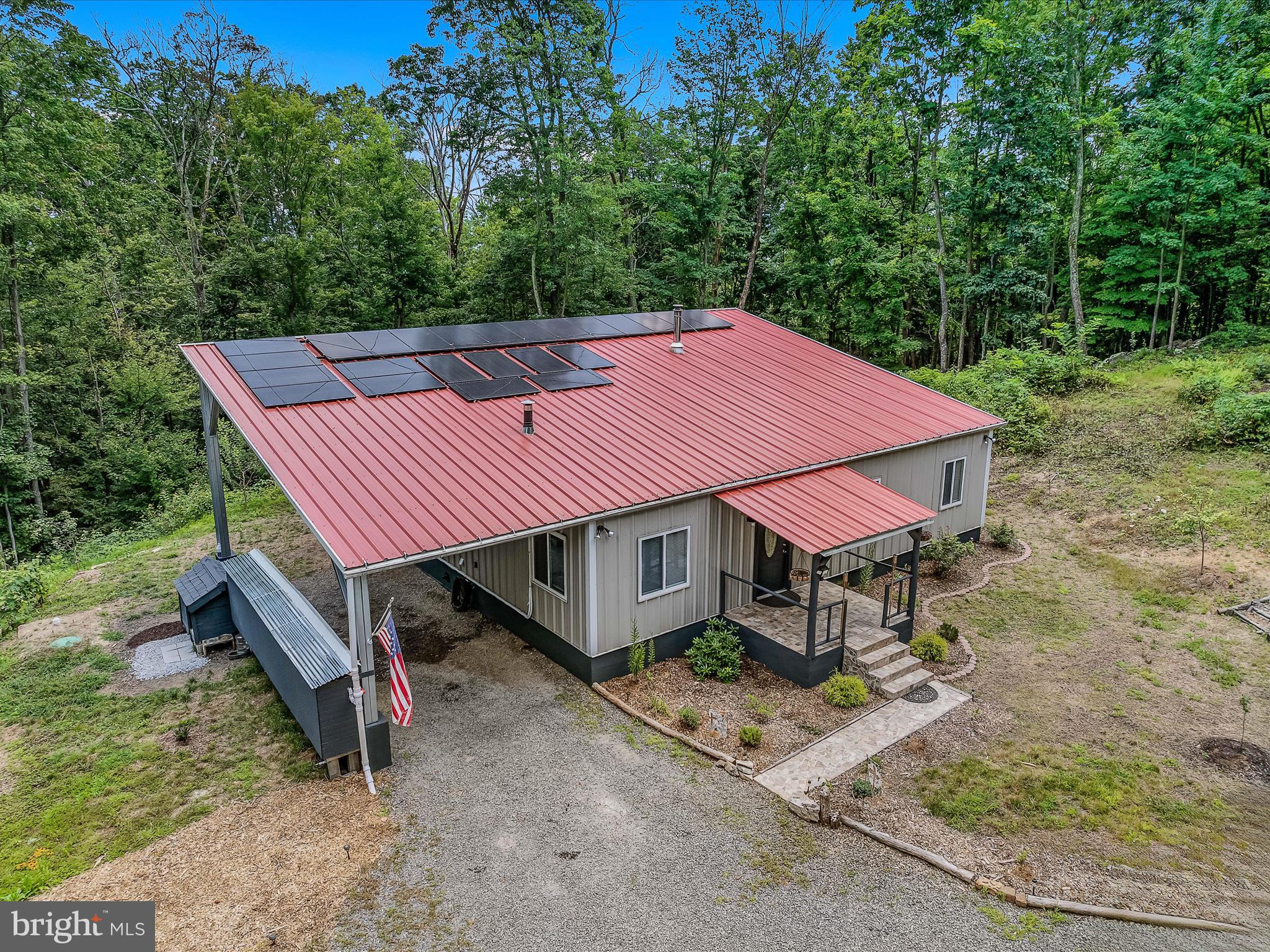 Welcome to 397 Happy Valley Lane a completely off-grid home! The current owner certainly had an eye for detail when building this fully solar powered home - upon walking in the front door you will immediately notice the beautiful tile flooring, the amazing wood cathedral ceilings, the exposed metal beams, and wood burning stove. The spacious Great Room is the perfect space to entertain family and friends; the open concept allows for you to be finishing up (or cleaning up) in the kitchen while still being able to enjoy the gathering. You will find beautiful tile flooring and the same wood ceilings in all three of the well-appointed bedrooms. The primary bedroom offers an attached bath with a large tile tub/shower combo. The smaller of the three bedrooms boast a wood burning stove (that is right - this home comes with not one, but two wood burning stoves!). The second bathroom is conveniently located just off the great room and boast a large tile shower. You will find the same wood used on the ceilings as accents in several areas throughout the home. Another amazing feature of this home is the arched entryways to each interior room featuring sliding barn doors. The front and back porches are both covered and boast exterior tile flooring. The 14x32 attached carport allows for plenty of space to park your vehicle or outdoor equipment. Outside you will also find a beautiful handmade stone retaining wall, 3 outbuildings (one of these being a chicken coop), a large already established garden, and (as if that isn't enough) there are 30 different types of fruit trees on the property. Can you imagine having all of this without having utility bills? The two 500lb batteries that store the solar to power the home are found in a loft area of the home. I would be remiss if I didn’t add that the electrical work has been done inside of the home and power poles are located along the road, so there is potential to be “on-grid” if you so choose. Another unique feature of the property is the 650 gallon rain water collection system the current owner has established. Imagine having all of this AND the convenience of town being approximately 15 minutes away! Looking for privacy? Serenity? To simplify your lifestyle? Then look no further! Whether you are seeking a full-time residence or a weekend get-away this home is a MUST SEE!