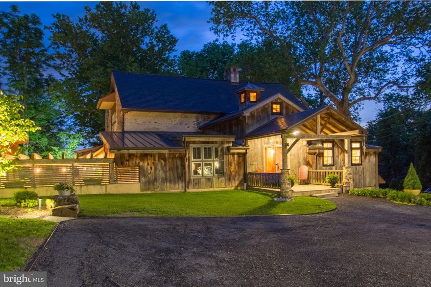 Welcome to the Barn at Ash Mill.
A quintessential Bucks County converted stone bank barn circa 1729.
This extraordinary property is situated on almost 12 bucolic acres encompassing both sides of one of Buckingham Township’s most desirable roads and conveniently located minutes away from the river town of New Hope, and historic Doylestown Pennsylvania with fine dining, shopping and entertainment. History abounds as it was once the studio of the renowned impressionist painter and designer of stained-glass windows George W. Sotter. He was mostly known for his association with the New Hope Art Colony. The 6,880+/- sq. ft. barn was completely and thoughtfully restored in 2012 including modern amenities while preserving the historic character and charm of an old barn. Featuring geothermal green energy heating and cooling, radiant floor heating, new roof in 2024, Anderson full divided light windows, security system with cameras, and fully integrated Sonos surround sound system. The expert craftsmanship is evident from the reclaimed weathered barnwood siding to the attention to detail and quality of materials throughout. Upon entering the foyer there is a feeling of comfort and spaciousness. A vaulted ceiling, exposed beams, plaster walls and a stone wall entrance that invites you into the massive great room. Here you’ll be amazed by the 17-foot-high ceiling, walls of
windows, post and beam structure and one of the four fireplaces located on the
property. The chef inspired kitchen is equipped with Wolf, Liebherr and Bosch appliances, custom
cabinetry, granite countertop, large barnwood and black walnut island, 2 copper sinks
and built-in banquet seating. Also conveniently located on the main level is the laundry room, powder room and the primary bedroom with two large walk-in closets. The ensuite bathroom has a vaulted
ceiling, a spacious shower and a clawfoot tub. The upper level consists of two bedrooms with exposed beams, large windows and a hall bath.
The lower level invites you to a large entertainment space with a stone fireplace, travertine floors, exposed beams, barnwood accents and a private ensuite bedroom.
There is also a utility room, gym, sunroom, library, wine cellar, and half-bath. The two-story pub room has stone and plaster walls, leaded stained-glass windows, stone fireplace, granite counter tops, custom bar wrapped in copper, glass front refrigerator/freezer, microwave/convection oven, galvanized sink and beer tap. An office/painter’s studio with brick floors can be accessed from the main living area or a private entrance. Virtually staged room do not reflect the original hardwood flooring. 
The rear exterior of the Barn boasts a spectacular entertainment area with multi-level bluestone patios, a pergola covered kitchen with high-end Twin Eagle appliances, a granite countertop and peninsula. Adjacent to the kitchen is a covered post and beam sitting area with a massive stone fireplace and brick walls with boulder outcroppings that blend seamlessly with beautiful views of rock gardens and split-rail fenced pastures beyond. A private enclosed saltwater spa is just steps away.
For the auto collector or car enthusiast there is a detached four-car garage with a built-
in work bench and storage room. There is also a detached one car garage located on
the property. A darling garden potting shed and a 14-tree organic fenced in orchard complete the rear
10+/- acres of the property. As you approach the front of the barn you are welcomed by a stone walled courtyard with brick and bluestone patios and a tranquil water feature.
Overlooking an additional 2+/- acres there are views of mature trees, lush greenery and a picturesque woodshed with a moss-covered roof.
Experience the ultimate in country living…. Live in a Barn!!