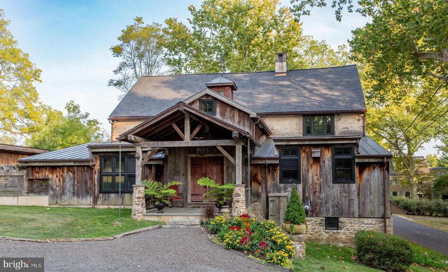Welcome to the Barn at Ash Mill.
A quintessential Bucks County converted stone bank barn circa 1729.
This extraordinary property is situated on almost 12 bucolic acres encompassing both sides of one of Buckingham Township’s most desirable roads and conveniently located minutes away from the river town of New Hope, and historic Doylestown Pennsylvania with fine dining, shopping and entertainment. History abounds as it was once the studio of the renowned impressionist painter and designer of stained-glass windows George W. Sotter. He was mostly known for his association with the New Hope Art Colony. The 9,000+/- sq. ft. barn was completely and thoughtfully restored in 2012 including modern amenities while preserving the historic character and charm of an old barn. Featuring geothermal green energy heating and cooling, radiant floor heating, new roof in 2024, Anderson full divided light windows, security system with cameras, and fully integrated Sonos surround sound system. The expert craftsmanship is evident from the reclaimed weathered barnwood siding to the attention to detail and quality of materials throughout. Upon entering the foyer there is a feeling of comfort and spaciousness. A vaulted ceiling, exposed beams, plaster walls and a stone wall entrance that invites you into the massive great room. Here you’ll be amazed by the 17-foot-high ceiling, walls of
windows, post and beam structure and one of the four fireplaces located on the
property. The chef inspired kitchen is equipped with Wolf, Liebherr and Bosch appliances, custom
cabinetry, granite countertop, large barnwood and black walnut island, 2 copper sinks
and built-in banquet seating. Also conveniently located on the main level is the laundry room, powder room and the primary bedroom with two large walk-in closets. The ensuite bathroom has a vaulted
ceiling, a spacious shower and a clawfoot tub. The upper level consists of two bedrooms with exposed beams, large windows and a hall bath.
The lower level invites you to a large entertainment space with a stone fireplace, travertine floors, exposed beams, barnwood accents and a private ensuite bedroom.
There is also a utility room, gym, sunroom, library, wine cellar, and half-bath. The two-story pub room has stone and plaster walls, leaded stained-glass windows, stone fireplace, granite counter tops, custom bar wrapped in copper, glass front refrigerator/freezer, microwave/convection oven, galvanized sink and beer tap. An office/painter’s studio with brick floors can be accessed from the main living area or a private entrance.
The rear exterior of the Barn boasts a spectacular entertainment area with multi-level bluestone patios, a pergola covered kitchen with high-end Twin Eagle appliances, a granite countertop and peninsula. Adjacent to the kitchen is a covered post and beam sitting area with a massive stone fireplace and brick walls with boulder outcroppings that blend seamlessly with beautiful views of rock gardens and split-rail fenced pastures beyond. A private enclosed saltwater spa is just steps away.
For the auto collector or car enthusiast there is a detached four-car garage with a built-
in work bench and storage room. There is also a detached one car garage located on
the property. A darling garden potting shed and a 14-tree organic fenced in orchard complete the rear
10+/- acres of the property. As you approach the front of the barn you are welcomed by a stone walled courtyard with brick and bluestone patios and a tranquil water feature.
Overlooking an additional 2+/- acres there are views of mature trees, lush greenery and a picturesque woodshed with a moss-covered roof.
Experience the ultimate in country living…. Live in a Barn!!