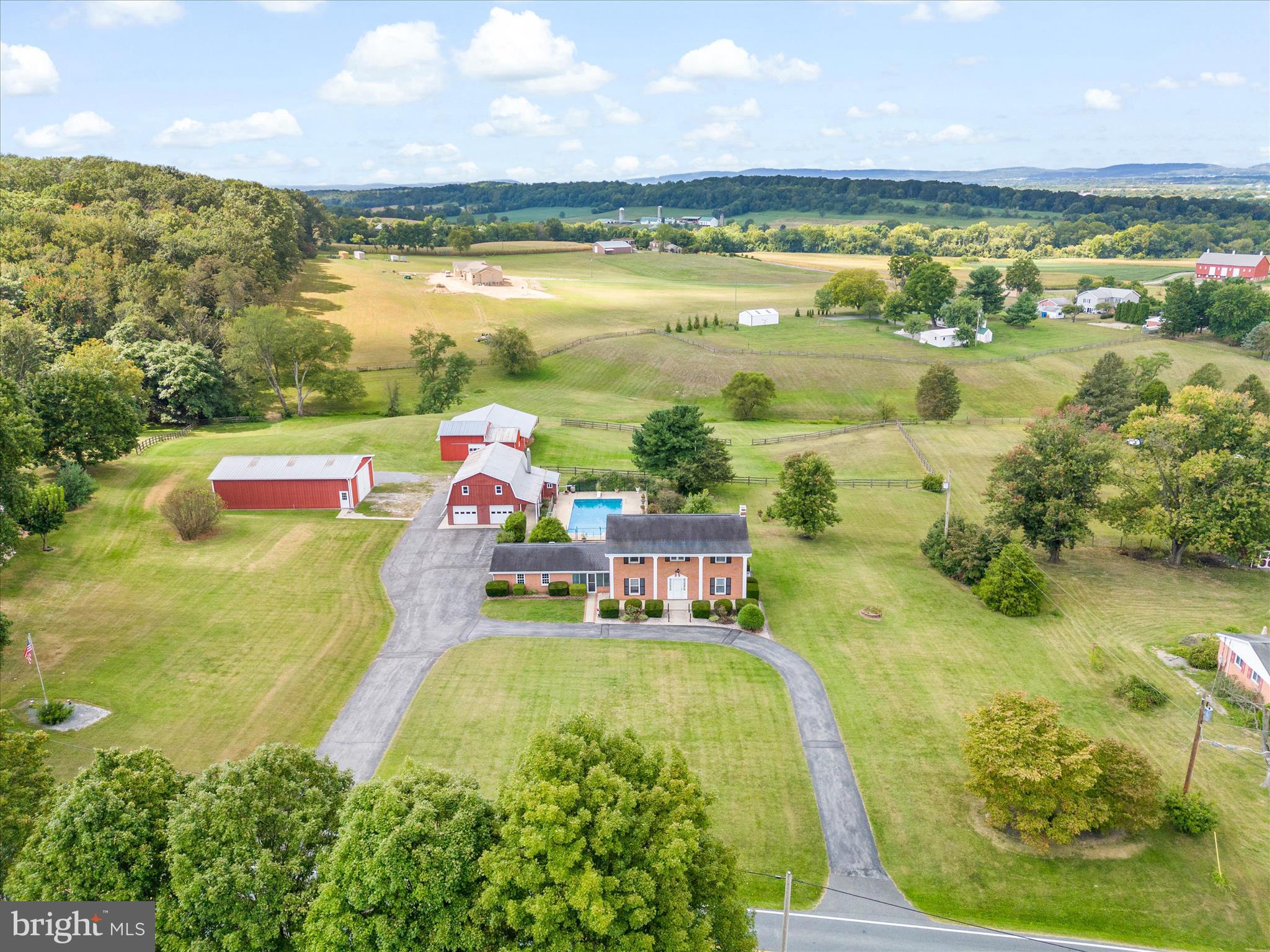 *OFFER DEADLINE: Tuesday Sept 9th at 3PM* This original-owner farmette offers a rare opportunity to own 11 scenic acres in the sought-after Urbana school district! This 4-bedroom, 2.5-bath brick colonial features a timeless layout, thoughtful details, and plenty of space to make your own. The main level includes a welcoming foyer, a spacious living room with built-in bookcases, a brick fireplace, and charming pocket doors that add both character and functionality. Hardwood floors lie beneath the carpeting in the living room, foyer, and hallway—ready to be uncovered if desired! The kitchen features granite countertops, laminate flooring, a large pantry, and space for a dining table. A separate room off the kitchen can serve as a formal dining room or a second living area, depending on your needs. A convenient half bath completes the main floor. Upstairs, you’ll find a generously sized primary suite with hardwood flooring and a dressing area that flows into a private bath. Three additional bedrooms—all with hardwood flooring—and a full hall bath round out the upper level. All bathrooms feature newer toilets, and the hot water heater was replaced in 2025. A laundry chute in both upstairs bathrooms and in the kitchen pantry adds everyday convenience. The partially finished basement includes a cozy living space with a wood stove, a flex room, laundry area, cold cellar, and utility room. A breezeway connects the home to a two-car attached garage. Out back, a large concrete patio leads to a fenced in-ground swimming pool, complete with a changing room/half bath for added convenience. Need garage or workshop space? You’ll love the detached three-car garage. Two front-entry bays are currently set up for entertaining, featuring cabinetry, a stove, refrigerator, and a commercial-grade three-bay stainless steel sink. The third bay, located on the side, is set up as a workshop. A full attic above provides excellent storage and is accessible by stairs. Additional outbuildings include a 30’x53’ Morton building with electric and a loft, and a 36’x57’ barn with a hayloft, tack room, two stalls, and a run-in. The property is partially fenced with one paddock, and a spring-fed creek meanders through the back field. Four parcels convey together, totaling +/- 11.13 acres, with a gated entrance off Baker Valley Road providing access to the rear lot. Peaceful and private, yet just minutes from commuter routes, shopping, and dining—this property offers the perfect blend of space, function, and location. Don’t miss the chance to make this your dream property!