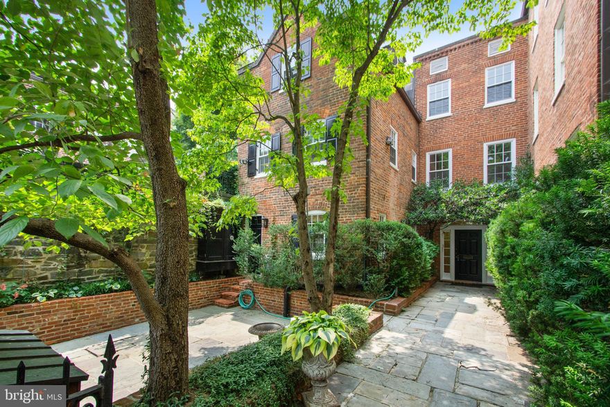 Listed on the National Register of Historic Georgetown Homes, 1406 34th Street NW is a quintessential Georgetown mini-estate, now available for sale for the first time in nearly 20 years. Dating back to the late 18th century, this magnificent residence was enlarged by combining four individual lots to create an extraordinary single garden enclosure. With its commanding street presence and rich architectural history, this property embodies the timeless elegance Georgetown is renowned for, offering a rare opportunity to own a piece of the city’s storied past.
Thoughtfully renovated and expanded, the historic residence features six bedrooms, five full baths, and one half bathroom in the main residence, as well as an additional separate carriage house. Every aspect of the home speaks to its rich legacy, from the traditional brick façade, gracefully adorned with climbing ivy, to the gated stone walkway leading to the main entrance set back from the street. 
Inside, expansive rooms bathed in natural light create an atmosphere of refined elegance. A spacious front bedroom with multiple closets, an updated en-suite bathroom with dual vanities, a frameless glass shower, and a large soaking tub make this level ideal for multi-generational living. This floor also includes staff accommodations with a living area, bedroom, full bathroom, and a laundry room equipped with multiple washers and dryers. 
The second level is designed for refined entertaining, with expansive reception rooms that effortlessly flow around a central courtyard. The interconnected Great Room, Dining Room, and Library, each graced with its own fireplace, seamlessly transition into one another. French doors open to an expansive terrace and beautifully landscaped gardens, where an enchanting blend of wisteria, hydrangeas, roses, and mature trees creates an idyllic setting for both peaceful moments at home and grand entertaining. The gourmet kitchen is appointed with quartz countertops, custom cabinetry, and premium appliances, including Bosch, Sub-Zero, and Viking, featuring dual sinks, refrigerators, and a professional-grade gas stove, complemented by a cozy breakfast room.
The impressive primary suite is found on the floor above, with its own expansive private terrace overlooking the beautiful gardens below. The room offers a generous walk-in dressing room and renovated primary bathroom with dual vanities, a free-standing soaking tub, and frameless glass shower with multiple shower features. There are two additional bedrooms on this floor with built-ins, and a hall bathroom. The top floor of the residence provides an additional bedroom, bathroom, and oversized hall closet.
A separate carriage house located at the rear of the property offers versatile use including a home office, gym, or art studio. The carriage house has direct access to the back alley and a private enclosed garage.  Additionally, a driveway at the front of the house ensures convivence for accessing the front of the property. 
This historic estate, host to numerous formal and day to day events, offers a rare opportunity to own a piece of Georgetown’s rich legacy. Ideally positioned minutes from the White House, Georgetown University, the Potomac River, and other landmark destinations, residents are placed at the very heart of the nation’s capital. This unique offering blends the elegance of a bygone era with the refined comforts of modern living, creating an unparalleled setting of both heritage and modern living.