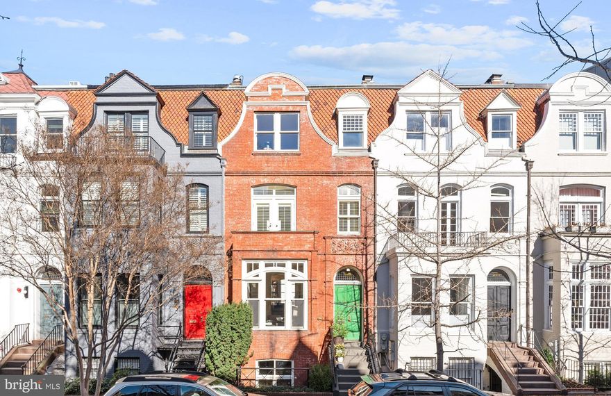 This quintessential Victorian row house is desirably located in the vibrant Dupont neighborhood. The beautiful brick residence was built in 1870 and has undergone extensive updates, while maintaining original details to preserve its historic character and charm. The house features an abundance of natural sunlight from oversized windows, which is further magnified by the high ceilings throughout. A lovely front garden and iron-railed stairway compliment the impressive façade of the house. Upon entering, a charming front vestibule with black and white tiled floors leads to the welcoming reception foyer. The foyer seamlessly transitions to the elegant living room, which has a south-facing bay window and a decorative fireplace with marble surround. Neighboring the living room is an exceptional family room/library. The room offers a wood-burning fireplace, built-in bookshelves, and a two-story wall of windows towards the rear of the home with lovely views of the rear garden. There is also a conveniently located wet bar with granite counters, cabinetry storage, and a mini refrigerator with an ice maker. The garden level below features an expansive gourmet kitchen with high-end appliances, a large center island, breakfast bar, abundant custom cabinetry, and a pantry. There is also a table space breakfast area with a built-in window seat and a window. The kitchen opens onto the sophisticated dining room, which accesses the two-story wall of windows and French doors opening to the rear garden and terrace. There is also a convenient powder room and multiple storage closets found on this floor. The second level is fully encompassed by the well-appointed primary suite. The generously proportioned primary bedroom is found towards the front of the house, with a wonderful south-facing window, a wood-burning fireplace, and a quaint private balcony overlooking the lovely tree-lined street below. There are multiple walk-in closets on this floor, as well as a large sitting room/office with custom built-in bookcases, two desks, cabinetry, and an additional balcony that overlooks the beautiful rear garden. The primary bathroom has lovely granite finishes and has a Jacuzzi tub and a separate shower with a seamless glass frame and multiple shower jets. The third floor, which is illuminated by a lovely skylight, provides two additional bedrooms, both with large double door closets, and a marble hall bathroom. The front bedroom features built-ins and a decorative fireplace and the rear bedroom overlooks the beautiful rear garden. There is also the added convenience of a washer and dryer, as well as a bonus room that can be used as a gym or a secondary office space. The impressive rear terrace and garden is exceptional for entertaining with wonderful privacy from layered bamboo and wisteria. There is also two-car parking. The house is within close walking distance to neighborhood favorite restaurants, shops, parks, and the Metro.