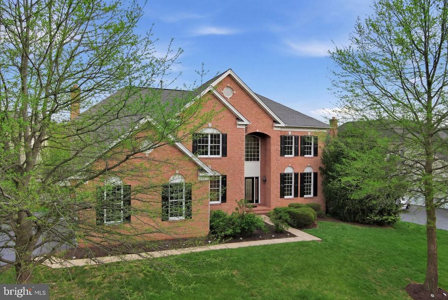 Open House Saturday May 9th 1:00pm - 3:00pm**Exceptional space in an exceptional community. Backing to trees on nearly a third of an acre in Belmont Country Club, this roughly 6,000 square foot residence features bright, open living areas, a fully finished lower level, and direct access to one of Northern Virginia’s most coveted lifestyles. Tree-lined streets welcome you home to a stately brick facade and three-car, side-load garage. Inside, a two-story foyer sets the tone with dramatic, sweeping stairs and a stunning chandelier. Formal living and dining rooms with hardwood floors provide versatile space for entertaining and everyday living, and the dining room includes a built-in butler’s pantry. The gourmet chef’s kitchen is equipped with a large center island, stainless appliances, and extensive storage including a deep walk-in pantry. A casual eat-in dining area flows into a sunroom with walls of windows overlooking the backyard. The family room is equally impressive with soaring vaulted ceilings and fireplace, opening out to the upgraded rear deck for effortless indoor-outdoor living. A private home office, laundry room, and powder bath round out the main level. Upstairs, four bedrooms all include walk-in closets and direct bathroom access. The primary suite features a vaulted ceiling, double vanity, spa tub, stall shower, and two walk-in closets. A secondary suite has its own private full bath, and two more spacious bedrooms share a Jack-and-Jill bathroom. The lower level is fully built out with an exceptional walk-up recreation room, a deluxe built-in bar, a dedicated home theater room, and a mirrored exercise and yoga area. A short walk-up provides direct access to the backyard. A bonus room with a full bathroom creates flexible guest space, and additional unfinished space provides extra storage. Outside, an expansive deck overlooks the grassy lawn and backing trees, ready for grilling, gatherings, or simply unwinding in this peaceful setting. Recent updates bring added peace of mind, including a new deck (2021), new roof (2022), a fully replaced upstairs HVAC system (2025), Protective window film in the two-story family room and sunroom, and a brand new, unused cooktop in the kitchen. Belmont Country Club residents enjoy access to an Arnold Palmer-designed 18-hole golf course, a 35,000 square foot clubhouse with dining venues and social programming, multiple pools, tennis and basketball courts, playgrounds, walking and jogging trails, a fitness center with dedicated studios, and the historic Belmont Manor Home. High-speed internet, cable TV, and full lawn and landscape maintenance are all included. The location puts you minutes from highly rated public and private schools, major shopping and dining, parks, regional trails, and convenient commuting routes. A home of this caliber, in a community this complete, does not come along often.