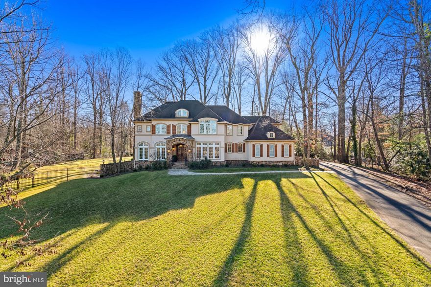 Timeless French country elegance, masterful design and a McLean best address on more than one acre. It’s a dazzling first impression that begins on the approach along Corbin Court with stately homes lining the way to the end of the cul-de-sac and a long private driveway entrance to this 5 bedroom custom home with 10 foot ceilings. The residence is slightly elevated just beyond the lush front lawn which creates powerful imagery before you even make it through the imported mahogany doorway. A double height foyer features French limestone floors accented by a fossil inlay. It’s thoughtfully designed to create an effortless flow from room to room. A formal living room is highlighted by a wood burning fireplace. The dining room is serviced by an oversized butlers pantry with wine chiller. A bay of windows floods the study with natural light. The great room featuring a 10 foot stone fireplace runs along the full width of the home with floor to ceiling views of the rear grounds and a sprawling stone terrace. A gourmet kitchen is built for the home chef and large scale entertaining with an eat in center island, prep sink, rich designer cabinetry, top of the line appliances, farm sink, walk in pantry and casual kitchen dining for more than 12. The main level also features a dish room, 2 powder rooms, large mud room and laundry room with a dog wash shower. 
A curved staircase with iron spindles is highlighted by an oversized French chandelier. The second level is designed with 4 bedrooms including a sweeping primary suite with a sitting room featuring a fireplace and large private deck. The primary bathroom is reminiscent of a five star spa retreat. A soaking tub and oversized shower are connected by a zen stone inlay. The bathroom suite includes two vanities, two water closets, large walk-in closet and a second full laundry room. The impressive ceiling height is carried through on the lower level. It’s an open entertaining floor plan with abundant fireside seating, kitchenette and wet bar, built in wine storage, dedicated dining, billiards room, theater room with tiered seating, gym, another full bedroom and bathroom plus a walk out to a large sunken stone patio. The quality of build well exceeds the expected with a 75 year + architectural shingle roof and a protective three coat hard stucco facade. It’s a total luxury package with a long list of ‘must haves’ for modern living at the highest level combined with a prestigious McLean location inside the Capital Beltway.