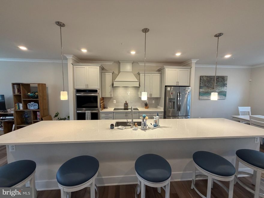 Awesome location in west OC! This 3-level townhouse, built in 2022 has upscale finishes throughout. Offering 3 spacious bedrooms plus a main level bonus room; 2 full bathrooms, and 2 half baths, this home blends modern comfort and coastal convenience. Relish open concept living with a large great room and dining area, and a gourmet kitchen featuring stainless steel appliances, quartz countertops, upgraded cabinets, stylish backsplash, and designer pendant lighting. Wide plank flooring and ceramic tile add warmth and elegance throughout the home. The owner’s suite begins with beautiful French doors, complete with a large walk-in closet and a luxurious en-suite bath with double sinks.  Additional features include a 2-car garage with driveway, a composite deck with vinyl railing, a paver patio.  Enjoy all that Sea Oaks Village has to offer, including a community pool, playground, pickleball and a basketball court. The front of the community also has commercial units including a sweet shop, golf store, 3 different gyms and a car detailing service to name a few.  Located just minutes from Assateague Island and Ocean City beaches. This has it all – modern finishes, flexible space, and an unbeatable location!