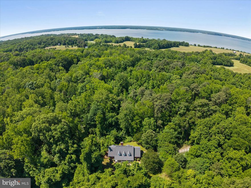 Tucked at the end of a long private driveway, this nearly four-acre property backs directly to Jefferson Patterson Park - 560 acres of protected woodland and Patuxent River shoreline that frame the home in lasting privacy. A peaceful, wooded setting like this is genuinely hard to find. Inside, 3,682 square feet live large. Real white oak hardwood floors run through a sun-filled main level that includes a dedicated home office and a spacious owner’s suite - all on one floor - with a dual-sink en suite, soaking tub, and walk-in closet. The kitchen is built for everyday life: a farmhouse sink, generous oak cabinetry, a full-size refrigerator and freezer, and not one but TWO pantries. Upstairs, oversized bedrooms with deep closets offer plenty of room to spread out, and a convenient main-level powder room rounds out the 3.5 baths. Recent updates make it move-in ready: a newer roof, an efficient two-zone heat pump system, and Tesla solar that keeps electric bills remarkably low - averaging around $150 a month. Add a welcoming front porch, a rear deck, a fully fenced yard, a water softener, and expansive attic storage, and the everyday details are handled.
All of this sits in the middle of Calvert County, the everyday conveniences of Prince Frederick, and the waterfront dining of Solomons Island — with no HOA. Come experience the quiet for yourself! Fireplace being sold as-is since it has not been used since homeowner has lived here.