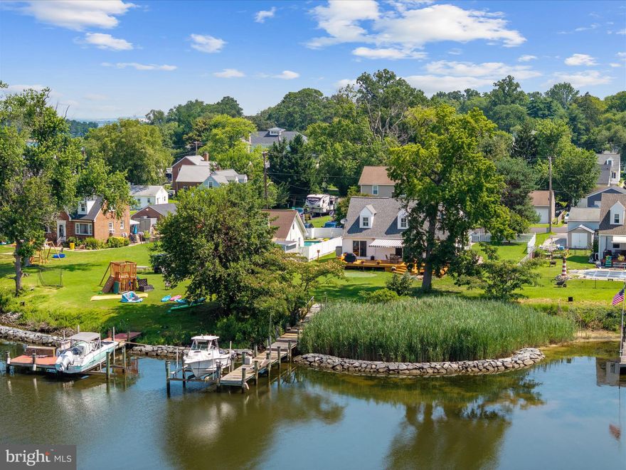 OPEN SATURDAY, 8/16, 12-2 PM!  NEW PRICE!  Welcome to this beautifully updated 3-bedroom, 3-bath water view  home with water access on the deep and protected waters of Stoney Creek, just off the Patapsco River. While the property is non-riparian, it includes a community dock with a private boat lift (approximately 9,000 lbs), providing easy access to boating, fishing, and exploring the Chesapeake Bay. The main level offers a bright and open floor plan with a spacious living and dining area, perfect for entertaining or relaxing while enjoying serene water views. The kitchen is equipped with modern stainless steel appliances, including an oven (2020), refrigerator (2022), and dishwasher (2023), along with ample cabinetry and counter space. A retractable awning extends your living space outdoors, creating a shaded area ideal for al fresco dining or sunset cocktails.

Also on the main level are two bedrooms—one with wide, unobstructed water views and the other with charming water peeks—along with a full hall bath. Upstairs, the primary suite is a peaceful retreat offering water views and a large en suite bathroom. The lower-level basement includes a full bath and small kitchenette, offering flexible space for a future guest suite, home office, gym, or hobby room.

Additional upgrades include Thompson Creek windows and sliding doors (2018), HVAC and split system (2017), roof (2023), gutters (2022), new flooring on the main level (2017), motorized roller shades (2022), and a sunroom added in 2017. The retractable Sunsetter awning will have new fabric installed prior to settlement. A detached 2-car garage offers convenient parking, extra storage, or space for a workshop.

Located in a water-privileged community with access to a park, beach, and community dock, this home offers the perfect blend of turnkey comfort and waterfront charm l—ideal as a full-time residence or weekend escape.  **Please note, this home is not waterfront as there is a community easement from the property line to the rip rap.  Please call for more info.**
