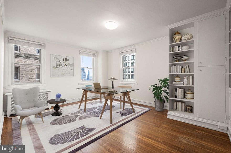 Perched on a high floor in the Rittenhouse Plaza, this corner one bedroom plus den, two bath residence offers exceptional light, space, and views in one of Philadelphia’s most sought-after locations on Rittenhouse Square. With three beautiful exposures, the home is filled with natural light throughout the day. The west-facing den enjoys lovely sunset views and features custom built-ins, creating an ideal office or sitting room. The expansive living and dining areas face north and east, capturing open skyline views and soft morning light. Original floors with mahogany inlay run throughout the home, adding timeless character and warmth. The generously sized kitchen offers gas cooking, side by side laundry, and ample workspace.    The spacious primary bedroom is both quiet and inviting, featuring built-in bookshelves and an en-suite bath with a window for natural light and ventilation. Storage is a standout feature of this home. A separate hallway offers four large closets and houses the second full bathroom, providing exceptional functionality. This residence presents a wonderful opportunity to customize a truly special home in one of Philadelphia’s rare New York-style prewar Co-ops. The Plaza is known for its classic architecture, private courtyard garden, attentive service, and unparalleled location. This pet-friendly building offers a 24 hour concierge and unmatched access to the best of Center City. The monthly co-op fee includes real estate taxes, Fios cable and internet, heat, water, sewer, and building maintenance. A one-time transfer fee equal to 2% of the purchase price is payable at closing. Nearby parking options are available for rent within one block.