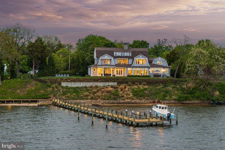 Standing proudly along the South River, just minutes from downtown Annapolis and the open waters of the Chesapeake Bay, this custom-built 2015 shingle-style residence captures the essence of refined waterfront living with a seamless balance of elegance, comfort, and connection to the outdoors. Thoughtfully designed and bathed in natural light, the home is positioned to take full advantage of its spectacular, ever-changing views.

The main level is anchored by a beautifully appointed primary suite, offering a private retreat with a custom-designed closet and a spa-inspired bath. A soaking tub perfectly positioned to overlook the pool and waterfront creates a serene daily ritual, complemented by a walk-in shower and refined finishes throughout. The living spaces flow effortlessly from the kitchen to the dining area and living room, creating an inviting setting for both intimate gatherings and larger-scale entertaining, all enhanced by walls of windows that frame the surrounding landscape and water views from every room

Upstairs, two ensuite bedrooms each enjoy sweeping views of the South River, along with private balconies that invite quiet mornings and sunset reflections. The home’s thoughtful layout ensures both privacy and connection, with each space designed to highlight the remarkable setting.

Outdoors, the experience is equally compelling. The inviting waterside pool and multiple stone patios serve as the centerpiece for summer living, surrounded by impeccable, professionally curated landscaping that enhances both beauty and privacy. At the water’s edge, a charming auxiliary structure offers endless flexibility, ideal as a studio, creative retreat, or convenient storage for waterfront essentials.

With 219 feet of shoreline and just under an acre of beautifully sited land, this exceptional waterfront setting is designed for those who truly embrace life on the water. A private deep-water, multi-slip pier equipped with two boat lifts makes it effortless to head out at a moment’s notice, whether for an early morning cruise, an afternoon of fishing and watersports, or a sunset run along the South River into the open expanse of the Chesapeake Bay. From leisurely days spent boating and exploring nearby coves to hosting friends dockside or simply enjoying the ever-changing views, this property offers a seamless connection to a lifestyle defined by freedom, adventure, and the enduring appeal of waterfront living.

Set within the sought-after Wild Rose Shores community on Ferry Point, this exceptional property delivers a rare combination of newer construction, thoughtful design, and an elevated waterfront lifestyle in one of the Annapolis area’s most desirable settings. Welcome Home!