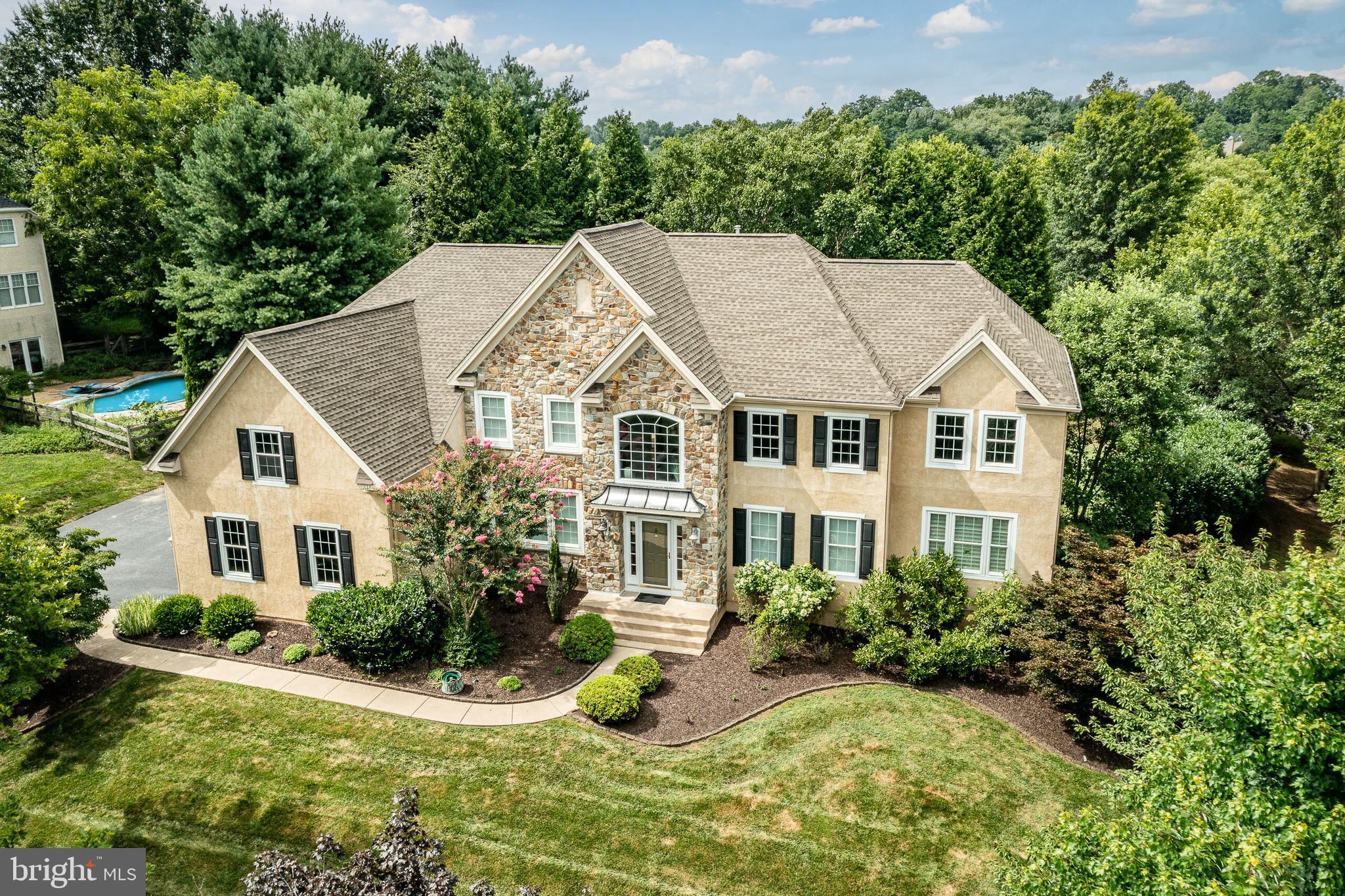 Welcome to 1031 Bucktail Way, a showstopping estate in sought-after East Bradford Township, Chester County! This expansive 4-bedroom plus home, with 5.5 bathrooms, offers an exceptional blend of luxury, functionality, and timeless style—nestled on a beautifully landscaped lot designed for entertaining and everyday enjoyment. Step inside the grand two-story foyer, where gleaming hardwood floors stretch across much of the main level. Flanking the entryway are the elegant formal dining room—featuring crown molding, an intricate chandelier, and triple front windows—and the spacious formal living room, perfect for entertaining. At the heart of the home, the sun-drenched two-story great room showcases oversized windows, a striking fireplace with marble surround, and seamless flow into the gourmet kitchen. The kitchen boasts granite countertops, stainless steel appliances, farmhouse sink, recessed lighting, and ample cabinetry. A massive center island offers bar-style seating, complemented by a bright breakfast area with sliders leading to a private deck—secluded by mature trees and greenery for ultimate privacy. A large laundry room with cabinetry and a wash sink adds convenience, while the main floor conservatory—featuring a walk-in closet and full bathroom—offers potential for an in-law suite or flexible living space. A powder room and abundant closet space complete the main level. Upstairs, the primary suite is a true retreat with a sitting area, large split walk-in closet, a private office, and a spa-like en-suite bath with soaking tub and tiled shower. A second primary bedroom features its own private bath and walk-in closet, while the third and fourth bedrooms share a beautifully updated Jack-and-Jill bathroom with new granite vanities, lighting, fixtures, and paint—each with its own walk-in closet. Head down to the finished walk-out basement, where natural light pours into the home gym, and a full bath adds extra functionality. The lower level opens directly to your outdoor oasis—a newly refinished in-ground pool surrounded by extensive hardscaping and plush, mature landscaping. The pool features new plaster, tile, coping, chlorinator, pump, and vacuum, creating a serene backyard retreat perfect for relaxing or entertaining all summer long. Additional highlights include a spacious three-car garage, two new gas HVAC systems with humidifiers, newer insulated low-E windows, and a newer roof. The original stucco was professionally removed and replaced with new stucco over a proper weep screed drainage system, along with new gutters, downspouts, trim, fascia, and soffits. This home is truly turnkey and impeccably maintained. Don’t miss the chance to own this incredible property in a prime location—schedule your private tour today!