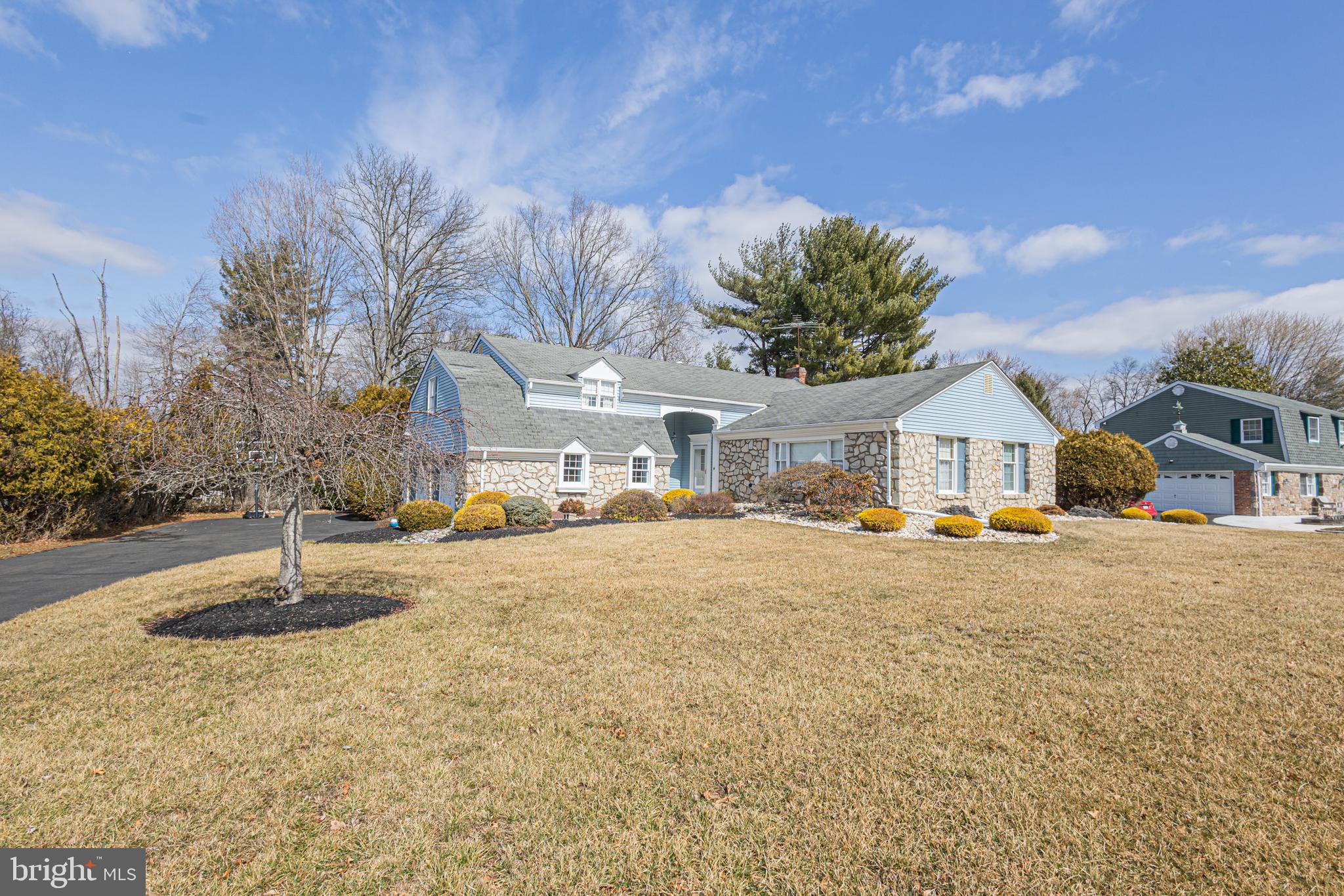 Waiting for new owners to bring their creative vision is this well-maintained, 4-bed split level home nestled on just over a half-acre lot in the serene community of Hillcrestshire just 10 minutes from downtown Newtown. A convenient covered front porch welcomes you inside to a cathedral ceiling foyer adorn with an accent wood beam presenting an immediate view of the natural light infused living room flowing seamlessly into the spacious rear dining room. The neighboring kitchen, open to the family room, offers plenty of cabinetry, a useful L-shaped island with built-in wine rack and highlights an oversized window in the breakfast nook allowing for soothing beams of sunlight. Step down into the nearby family room with its beamed ceiling where you can unwind and cozy up by the brick surround, wood burning fireplace while spending time with family conversing about the day’s events. An adjacent hallway leads to a convenient half bath and bonus/bedroom as well as a laundry/mud room with side door access to a covered outdoor patio where you can enjoy your morning coffee while listening to the sounds of nature. Upstairs at the top of the landing is the primary suite ornamented with a custom makeup vanity, ample closet storage and its own full bath with corner shower. A second bright bedroom offers cathedral ceilings and an arched entrance to a private, connected sitting room making it a perfect cozy reading nook. Completing this level are two sizable bedrooms, one currently utilized as an office/sitting room with a full wall of built-ins, which share a full hall bath with separate double sink vanity and tub area. Downstairs, the updated basement with its openness and built-in bar offers endless possibilities to extend living space along with an abundance of storage. Additional amenities include an attached 2-car garage with side entrance and pull-down attic storage. Award-winning Council Rock School District.