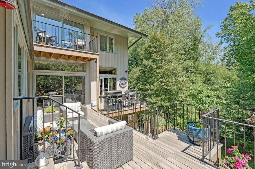 Tucked away in the highly sought-after Balmacara neighborhood, this stunning 5-bedroom, 4.5-bath contemporary residence impresses from the moment you enter its private gated courtyard. Filled with natural light from expansive windows throughout, the home seamlessly blends modern updates with timeless architectural charm, overlooking its own private forest.
The open-concept main living area is anchored by a striking stone-column fireplace that beautifully defines the space while maintaining an airy flow ideal for both everyday living and entertaining. At the heart of the home, the renovated kitchen features a large communal island, stainless steel appliances, and abundant prep and storage space. Just off the living area, a sophisticated office with floor-to-ceiling shelving opens directly onto the spacious rear deck, while an additional private den offers even more flexible living space and extensive built-in storage.
The luxurious owner’s suite serves as a peaceful retreat, complete with a private balcony overlooking the wooded backyard and a beautifully updated spa-inspired bath featuring split quartz dual vanities and generous cabinet storage. The suite’s versatile layout also provides the perfect opportunity for a sitting room or private office. Each secondary bedroom is filled with natural light and character, and the two carpeted bedrooms feature sand-in-place hardwood flooring underneath. Newly renovated full bathrooms further elevate the home’s thoughtful design. Main-level suite features an adjoining private bathroom with shower that includes grab bar and built-in, fold-down bench for adaptable seating, safety and comfort. 
Designed with both comfort and convenience in mind, the home also includes a wet bar, dedicated laundry room, and a charming sunroom surrounded by windows that showcase serene outdoor views year-round. Step outside to enjoy the expansive rear deck overlooking mature trees, a creek, and abundant wildlife — an ideal setting for relaxing or entertaining guests. Below, the in-ground pool and hot tub are surrounded by lush landscaping, creating a truly private outdoor oasis.
An additional parcel across the creek conveys with the property, offering a rare arboretum-like setting and enhanced privacy. The unfinished basement provides tremendous storage and future expansion potential, while built-in exterior-access storage is perfect for lawn and garden equipment
Ideally located inside the Beltway on a quiet cul-de-sac, just one stoplight from Maryland and the GW Parkway, within walking distance to Langley High School, and only minutes from downtown McLean, this exceptional property offers the perfect balance of privacy, nature, and convenience. Schedule your private tour today!