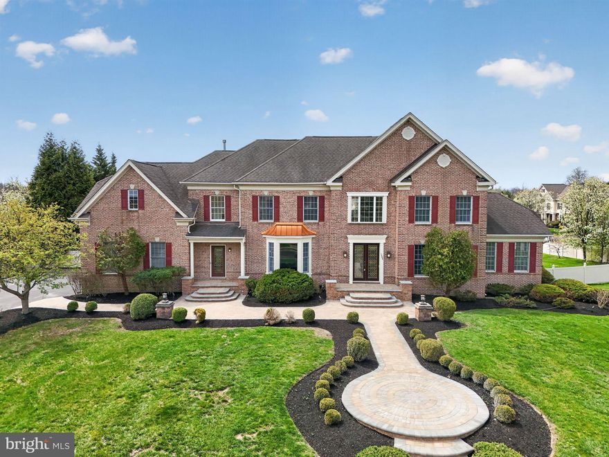 Located in the highly sought-after Highgate community of Ambler, this exceptional residence offers six bedrooms, five full baths, and two half baths across a meticulously maintained 1.34-acre corner lot. Surrounded by mature landscaping and perimeter plantings for ultimate privacy, the home reflects a remarkable level of craftsmanship, thoughtful design, and extensive upgrades. A stately brick front and newly redone paver walkways welcomes you to this fine home. Upon entering, the foyer makes an immediate impression with elegant marble flooring and a sweeping staircase featuring a custom, hand-carved walnut banister. To the right, the formal living room offers detailed custom molding and rich hardwood flooring, which flows seamlessly into an adjacent light-filled conservatory. This versatile space, featuring refined millwork and a full wall of windows, is ideal for a music room, library, or playroom. The formal dining room is designed for memorable gatherings, featuring an elegant chandelier, coordinating sconces, and beautifully crafted woodwork. The gourmet kitchen balances sophisticated aesthetics with high-end functionality, boasting custom marble countertops, a five-burner gas stove, and a massive center island crafted from a single slab of thick marble. Integrated storage solutions, including dedicated spice and condiment drawers, complement the walk-in pantry. For daily convenience, the laundry and mudroom feature a separate front entrance and direct access to the three-car garage. The kitchen opens to a bright breakfast room with direct access to the wraparound composite deck and gazebo, creating an effortless indoor-outdoor flow. The spacious family room is a showstopper, featuring coffered ceilings with gold accents, a soaring stone fireplace, and an expansive wall of windows. The main level also includes a well-positioned powder room and a first-floor bedroom suite with a full en suite bath, offering essential flexibility for guests or multi-generational living. Upstairs, the primary suite serves as a private retreat with backyard views, a tray ceiling, and a dressing room with vaulted ceilings. The suite features multiple storage areas, including an expansive custom walk-in closet and a secondary closet with a mini fridge. The marble-finished en suite bath includes dual vanities, a soaking tub, and a separate stall shower. Additional second-floor bedrooms are generously sized, featuring hardwood floors and ample light, including one with a private en suite and two connected by a Jack and Jill bath. The walk-out lower level significantly expands the home’s capabilities, featuring a dedicated spa area with a six-person jacuzzi, sauna, and steam shower. A second kitchen and large gathering area provide the perfect setup for an in-law or au pair suite. This level also includes a fitness room, game room, and a bright sixth bedroom with a walk-in closet and an additional powder room.  The exterior is truly unparalleled. The expansive maintenance-free deck overlooks a beautifully designed paver patio and a magnificent, heated saltwater pool. The pool area is enhanced by a pool house with two gazebos framing a full bath and changing rooms. The entire expansive yard is fenced for privacy and play. Entirely redone on the inside with new trim, custom millwork, and ornate fixtures, this home is an absolute BINGO for multi-generational families. Enjoy close proximity to Route 309, the PA Turnpike, the Power Line Trail, Simmons Elementary, Germantown Academy, golf clubs and the premier shopping and dining of Ambler.