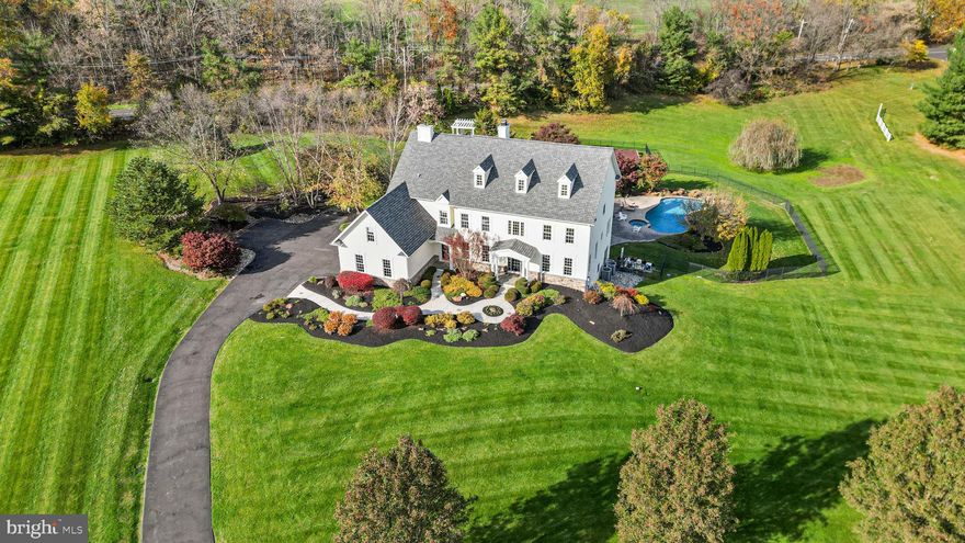 Two beautiful holly trees grace the driveway entry to this palatial Upper Makefield estate on three luscious acres just outside of New Hope and Peddlers Village – and located within the award-winning Council Rock School District! Situated on a cul-de-sac of elite homes, this location is second to none and truly speaks to living in the ‘heart’ of Bucks County! Artful hardscaping leads to the covered front porch and into the dramatic foyer of this home complete with marble floors and a turned staircase! The living and dining areas at the front of this home feature lighted coffered ceilings, creating a warm rich ambiance to welcome guests into your home. The main level truly has an open floorplan with hardwood throughout, a bright white updated eat-in kitchen, gourmet appliances (Sub Zero, Gaggenau, Thermador and Bosch),  a desirable center island, and a dual-sided stone gas fireplace! A wonderful year-round sunroom enlarges this space and encourages relaxation while watching nature’s show of colors change from season to season! Atrium doors lead to the wrap-around deck for enjoying barbecues and al fresco dining during the warmer months. The two-story family room with its wall of windows allows for conversation with friends and family while enjoying libations before dinner and taking in the stunning backyard oasis! Just off the family room, you will find a powder room and the office (or in-law bedroom) with ensuite bath! This room features built-in cabinetry and French doors for privacy with plenty of windows for an abundance of natural light. The main level includes a convenient front entry door to a large cloakroom – perfect for the family coming home from activities to have a drop zone for jackets, backpacks, and shoes. In addition, there is a huge laundry/mud room with side-entry. The upper level boasts a magnificent owners’ suite with volume ceilings, two-sided gas fireplace, custom-designed built-in cabinetry, and expansive owners’ bath with walk-in closets and organizers. This suite offers a spacious outdoor deck for reading, enjoying your morning coffee, or soaking in the sun! The upper level also features hardwood floors throughout! There are three additional bedrooms – one with an ensuite (guest) bath and the other two bedrooms share a Jack and Jill bath! All bedrooms have walk-in closets with custom-designed shelving! The lower walk-out level of this amazing residence offers an unbelievable recreation space and another full bedroom and bath! Your extended family can visit and enjoy fabulous accommodations such as a second media/family room, workout room, a third two-sided gas fireplace, private office, and an outstanding wine tasting room with wine cellar for displaying your private collection! The outdoor oasis is astounding with an inground swimming pool with hot tub, two Koi ponds, fire pit area, and a gazebo – making the sprawling three acres at 1 Windy Hollow Road a ‘staycation’ resort! There are so many special details, you must come and view, in person, to appreciate all this home has to offer! You will not hesitate to make this extraordinary sanctuary yours today!