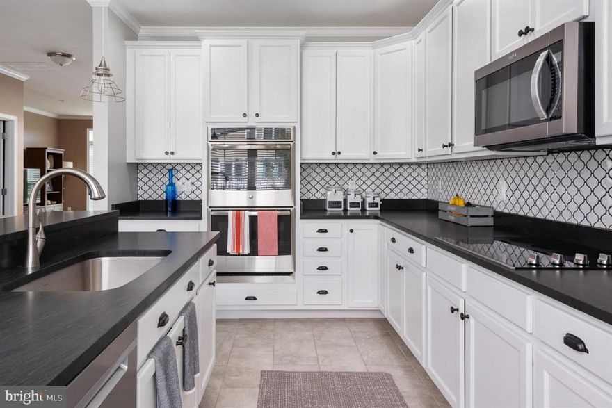 Beautiful 2300 square ft. END UNIT townhome in the amenity filled Ellendale community. 4 bedrooms, 4 baths, lots of light and windows.  Walk in to an inviting foyer with new hardwood floors and crown molding.  First floor bedroom and full bath in this floor and door that leads to the two car garage with rear entry.  Second level is a spacious, natural light filled family room with enough space for both entertaining and an office.  Hardwood floors and a brand new GOURMET kitchen with top of the line appliances - double wall ovens, built-in microwave, electric cooktop, fridge and dishwasher with 42 inch cabinet, backsplash and natural black granite countertops.  Center island offers more cabinet space and seating and it overlooks the full size dining room area.  New large TREX deck with enough space for seating AND patio set and grill.   Upstairs you will have two additional bedrooms and a full bath PLUS an owners Suite with new hardwood floors, a walk in closet, and  an en-suite completely renovated bath with shower and soaking tub, custom wall and floor tile and double vanity.  Laundry with stacked washer and dryer and storage.  Entire home has been freshly painted and all the windows, doors and siding were replaced in the last two years.  Community offers a pool, clubhouse, tot lot, fishing pier with floating dock, walking train and boat storage.  All this within one mile from the Chesapeake Bay Bridge!