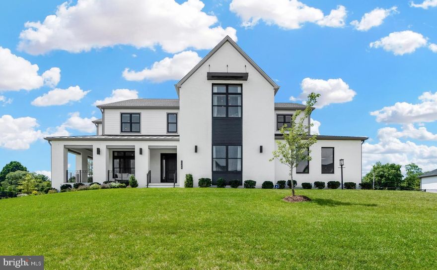 DON'T MISS THE VIRTUAL WALK THROUGH VIDEO! Extraordinary award-winning Warhol Modern Farmhouse in Sought-after Arden Community, sitting on the best private lot, directly across from the Model Home.  Superb location, just minutes away from Tysons Corner, Metro stops, entertainment, shopping and lots more! This home is enriched with lots of additional upgrades and premium finishes, plus an ELEVATOR. The grand wraparound porch leads to the interior of a modern but elegant home. Inside, is a stunning 2-story foyer with a turnaround oak staircase opening to a formal dining room/living room and study with custom built-ins. The Chef's gourmet kitchen and separate full prep kitchen are the heart of the home, featuring top-tier appliances, Quartz countertops, beautiful quartz waterfall island, lots of cabinet space, and a dream walk-in pantry. The luxury outdoor living, complete with a cozy 60" Primo fireplace, a retractable screen, integrated space heaters, two 15' multi-panel stacking doors, seamlessly blends indoor and outdoor spaces, perfect for entertainment all year round. The main level also features, a light-filled great room with 60" Primo fireplace, a casual living area/morning room, mud room, and a multigenerational living space with bedroom, full bath and walk-in closet. Upstairs, you will find 4 bedroom suites, including the luxurious primary suite with ultra grand bath, oversized shower, huge walk-in closet and walk-out to a terrace with 12-foot stacking doors leading to a large loft area/family room, plus laundry room. The lower level is perfect for entertainment, featuring a huge rec room, an exercise room with mirror wall, wet bar with wine fridge and dishwasher, and unfinished area with rough-in plumbing for bathroom for future bedroom. This home also features a 3 car garage with addition storage, gas line for outdoor grill, electrical car charger port, motorized blinds and so much more!