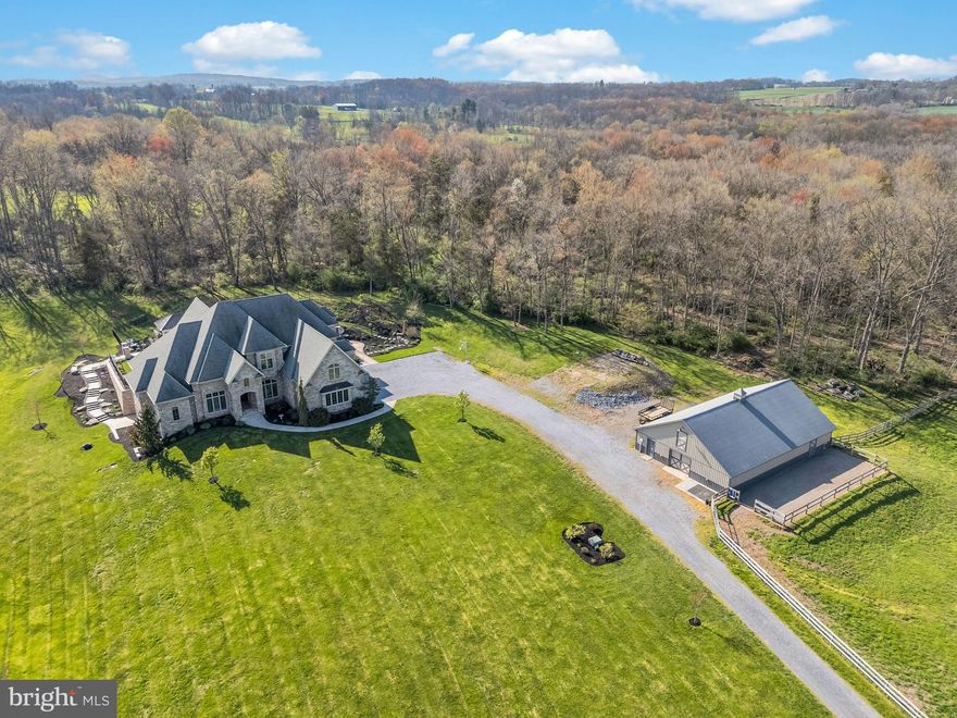 Discover unparalleled privacy and luxury in this stunning mountain stone single-family home, nestled on 17.3 breathtaking acres in Hershey. Just 15 minutes from the conveniences of downtown Hershey, this one-of-a-kind estate offers over 8,000 finished square feet, a 4-car garage, 6 bedrooms, 4 bathrooms, an inground heated saltwater pool, dual geothermal heat pumps, a whole house generator, and an array of high-end features that make it truly unlike any other property in the area. The entire exterior showcases exquisite mountain stone craftsmanship and attention to detail throughout.  This rare combination of privacy, acreage, luxury finishes, and world-class entertainment spaces makes this estate a true legacy property in Hershey.   Set on land enrolled in the Clean & Green program, the property provides complete seclusion while still being conveniently located.   Total acreage includes a separately deeded building lot attached  giving you the rare opportunity to expand your acreage even further. Outdoor and equestrian enthusiasts will love the manicured horse trails that span the entire parameter of the 17 acres along with the 60x40 pole barn complete with storage loft, a full bathroom, and room for an office. The barn includes two fenced pastures and room to expand — perfect for horses, cars, hobbies, or additional storage.  Inside, the dramatic 17-foot vaulted coffered ceilings in the great room set the tone for this exceptional home. The thoughtfully designed first-floor layout includes a formal dining room, spacious office with barrel ceiling, a chef’s open-concept kitchen with eat-in area, secondary living room, and a luxurious first-floor primary suite wing. The primary bedroom offers a trayed ceiling, oversized windows overlooking the pool and surrounding woods, and a spa-like ensuite bathroom featuring dual vanities, a luxurious soaking tub, a beautifully tiled shower, featuring a rain head, body sprayers, and custom user settings. A professionally designed California Closets walk-in completes the retreat.  The open-concept family room has been carefully thought out and professionally designed with entertaining in mind, offering a seamless design and flow between the living area, kitchen, eat-in kitchen, covered patio and pool. The living room boasts a trayed ceiling, gas fireplace, hardwood floors, custom wood trim, and large 7-foot windows, which flood the house with natural light. The kitchen, fit for a chef, is outfitted with high end Viking commercial appliances to include an 8 burner Viking range with griddle, commercial hood, Viking commercial counter depth refrigerator, and recessed speakers. The kitchen island is the meeting point for the entire family, offering granite countertops, sunken sink, and a built-in microwave drawer.  Step outside to an entertainer’s paradise: a massive 1,500+ sq ft outdoor living area featuring a covered patio, sunken propane firepit, custom outdoor kitchen, and a second covered entertaining space. Relax in the heated, inground saltwater pool, surrounded by professionally designed hardscaping and landscaping. The pre-wired landscape lighting creates a magical ambiance at night. The property also includes a full-sized sand volleyball court, the perfect addition for those warm summer days.  The partial walk-out basement is designed for a possible in-law suite or an entertainer’s dream, boasting over 3,000 sq ft with 10-foot ceilings and the same craftsmanship provided in the rest of the house. Highlights include a second full kitchen with a large bar with seating for 8, a living area complete with its own outdoor seating area and natural light, a state-of-the-art theater room with surround sound and electric reclining seats, a billiards room, a display wine room, a professional home gym, and two bathrooms, one being a full bath. Whether you’re looking for a private family compound or a sophisticated retreat, this home delivers on every level.