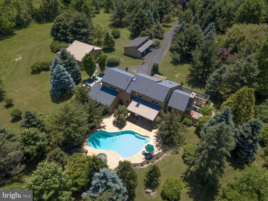 Visit https://bit.ly/Wildernest_3Dtour for a 3D walkthrough, and https://www.seetheproperty.com/u/277417 for photos, floorplans & more! A quiet country road and a meandering Cooks Creek leads to Wildernest, a private sanctuary perched atop a secluded Bucks County hillside.  There are views of pristine countryside from every vantage, where only a distant farm can be spotted on the horizon and nights are bejeweled with starlight.  At Wildernest, cedar, stone and glass combine to create a home that fits its environs comfortably and gracefully.  Perfectly-positioned in the center of 9.44 acres, with a glorious southern exposure, the home is bathed in light and features a floor plan of spacious rooms and ceilings that seem to reach for the sky. There are appointments of natural stone and custom woodwork throughout. The gourmet kitchen was designed with care, boasts top-of-the-line appliances, and offers an amazing ambiance overlooking pool and deck beyond.  A first floor guest suite is perfect for out of town guests, while the living room with fireplace, family room, and the solarium with hot tub will delight. The second floor has two more bedrooms and a master suite and balcony overlooking long distance vistas. Specimen plantings accent this hilltop retreat at every curve of the path and turn of the season.  Finally, the separate cottage is a getaway for guests and family members and could also be a space for a home office. An attached greenhouse and additional garaging for three cars are the final complement.