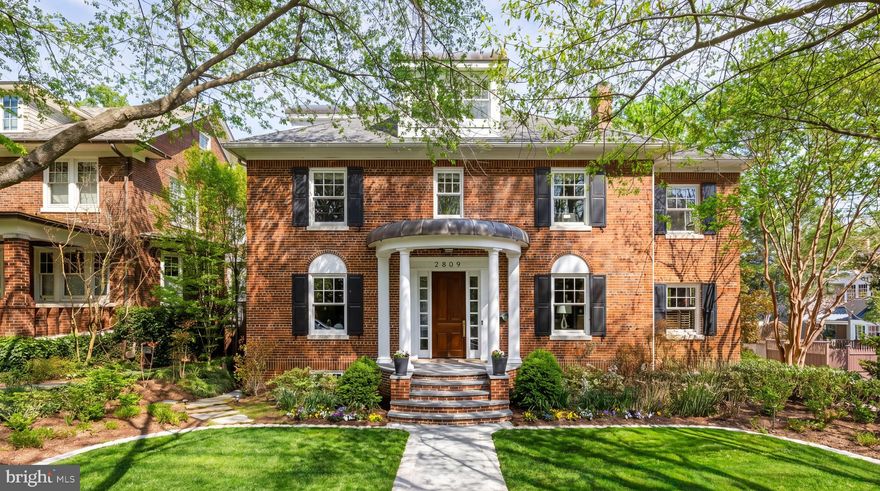 Set along a quiet, tree-lined street, 2809 34th Place NW is a residence defined by scale, privacy, and a composed architectural presence. Elevated above the street and introduced by a columned portico, the home opens to a light-filled foyer and central staircase, establishing a calm and refined sense of arrival.

The main level unfolds with quiet intention, where formal rooms and everyday living spaces coexist with fluidity. The living room, centered on a fireplace, is filled with natural light throughout the day and is equally suited for quiet mornings or evenings in company. The dining room continues this sense of proportion, accommodating larger gatherings while remaining inviting for more intimate occasions. A wood-paneled study with built-in shelving offers a private retreat, set just apart from the home’s primary flow.

Thoughtfully positioned between the dining room and kitchen, a sizable butler’s pantry introduces an added layer of functionality and discretion. Outfitted with a second dishwasher, sink, wine refrigerator, and generous counter space and cabinetry, it functions as a dedicated preparation and staging area, supporting seamless entertaining while preserving the kitchen’s sense of composition and ease.

Toward the rear, the home transitions into a more relaxed setting. The family room, anchored by a fireplace and oriented toward the surrounding grounds, becomes a natural place to gather. Just beyond, the kitchen is both functional and considered, centered around a substantial island that encourages daily life to unfold with ease. Paneled double refrigerators, double wall ovens, and a Viking gas range are seamlessly integrated, while the adjacent breakfast area offers a quieter place to begin the day.

From here, the connection outdoors is effortless. A deck extends from the main level, overlooking the pool and stone terrace below. Afternoons give way to evening, whether spent by the water, dining al fresco, or simply stepping away for a moment of quiet. Enveloped by greenery, the setting offers a sense of complete privacy.

Upstairs, the home continues with a graceful sense of separation and flow. The primary suite is set apart and accessed via its own staircase off the family room, creating a true retreat. Centered around a gas fireplace, the bedroom incorporates a sitting area and wet bar designed for daily living. The bath is finished with dual vanities, a soaking tub, and a walk-in shower, complemented by multiple dressing areas with custom built-ins. Additional bedrooms are thoughtfully positioned, each generous in scale and served by well-appointed baths. The top level features a vaulted ceiling suite with its own full bath, ideal for guests or extended stays.

The lower level mirrors the home’s scale and continuity. A large recreation room anchors the space, accompanied by a secondary sitting area and a dedicated gym or wellness room. A guest bedroom and full bath are tucked away, with ample storage throughout. A detached two-car garage is positioned at the rear of the property.

2809 34th Place NW unfolds gradually, each space building upon the last. Defined as much by feeling as by function, it offers a rare balance of comfort, elegance, and quiet sophistication.