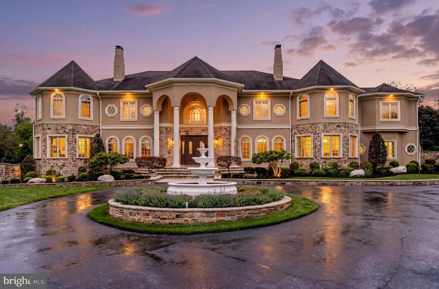 Built in 2013 and privately set behind gates in Potomac’s prestigious Palatine Community, 11900 Centurion Way is a residence of extraordinary scale, beauty, and sophistication. Gracefully positioned on manicured grounds with a sweeping circular drive and fountain arrival, this exceptional estate evokes the ambiance of a five-star European resort while offering the warmth and comfort of a truly livable home.
Designed with timeless architecture and impeccable attention to detail, the interiors are flooded with natural light through soaring arched windows and dramatic walls of glass. A breathtaking two-story family room anchors the home, where elegant proportions, refined millwork, and seamless views of the resort-style grounds create an atmosphere both grand and inviting.
The residence offers 6 spacious bedrooms, 7 full bathrooms, and 2 elegant powder rooms. The designer kitchen is as beautiful as it is functional, featuring oversized quartz islands, custom cabinetry, generous gathering spaces, and effortless flow into the home’s entertaining and family areas. An additional catering kitchen, thoughtfully designed for everyday cooking and large-scale entertaining, provides both convenience and discretion.
The outdoor experience is simply spectacular. Expansive stone terraces unfold into an extraordinary private retreat complete with a stunning resort-style pool and spa with cascading water features, an elegant pool house, outdoor lounge areas, a grilling station, a fireplace, lush landscaped gardens, and tranquil waterfall features. The professional-size tennis and basketball court further elevates the estate into a true lifestyle property designed for recreation, celebration, and serenity.
The luxurious owner’s suite offers the feel of a private sanctuary, complete with a sitting room and spa-inspired bath featuring heated floors and a steam shower. Each additional ensuite bedroom has been thoughtfully designed to provide exceptional comfort and privacy.
The walkout lower level rivals premier luxury clubs, offering expansive recreation and entertaining spaces, a dramatic theater room, wet bar, fitness area, and seamless access to the outdoor living areas and fire pit terrace. Even the smallest details were thoughtfully considered, including dedicated pet showers and multiple spa-like steam showers throughout the residence.
Additional features include a four-car garage, four-zone HVAC, whole-house generator, and exquisitely curated finishes throughout.
Rarely does a residence combine such grandeur with warmth, privacy, and effortless elegance. 11900 Centurion Way is more than a home. It is a statement of timeless luxury and elevated living.