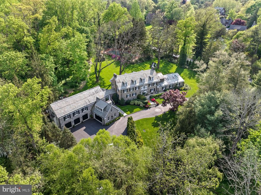 Welcome to 221 South Aberdeen Avenue, a hidden gem quietly nestled on two breathtaking acres in the heart of South Wayne, where the TAXES HAVE BEEN REDUCED and are reasonable for an estate property of this grandeur!!This grand stone estate, constructed on all four sides, has remained one of Radnor Township’s best-kept secrets for nearly a century. Surrounded by lush, mature landscaping and offering unmatched privacy, it’s a rare opportunity to own a true legacy property within walking distance to downtown Wayne. Step inside to an expansive front-to-back Foyer capturing views of the backyard oasis with stunning fountain setting the tone for this grand dame. Flanked by a formal Living Room with a floor-to-ceiling bay window and spectacular fireplace, and a Dining Room with deep windowsills, the home is filled with natural light and timeless charm. A cozy Breakfast Room with its own fireplace connects seamlessly to the updated Kitchen featuring high-end appliances, custom cabinetry, and granite countertops, maintaining an open feel ideal to create gourmet meals for entertaining and everyday living. From the Kitchen, enter the   glorious Sunroom with a hand-painted ceiling—an architectural jewel that connects the original home to the dramatic Great Room addition. With soaring ceilings, a custom hand-carved bar, and stained glass windows that fill the space with color and warmth, the Great Room is the ultimate entertainer’s dream. French doors open to a large deck that overlooks the expansive grounds, providing seamless indoor-outdoor flow. Off the Great Room is a private Office and Full Bathroom, making this area ideal for a guest suite, in-law accommodations, or a secluded work-from-home space. Whether hosting a garden party or enjoying a quiet morning coffee, the outdoor spaces offer unparalleled peace and privacy. Upstairs, the gracious Second-Floor landing features a beautiful arched window and window seat that add charm and character. The luxurious Primary Suite is a true retreat, offering His and Her Bathrooms and an incredible walk-in closet with exposed stone walls. Three additional Bedrooms and Two Full Baths provide ample space for family and guests. A well-positioned Laundry Room sits just off the back staircase, which offers direct access to the kitchen, making daily living effortless. The Third Floor features Two more Ensuite Bedrooms, perfect for extended family, guests, an au pair, or older children seeking their own space. These Upper-Level Rooms continue the home’s tradition of gracious scale, classic details, and exceptional versatility. Completing the home is an oversized 5-car garage—a rare and highly sought-after feature on the Main Line—paired with a convenient Mudroom area that keeps daily comings and goings beautifully organized. Behind the scenes, all major systems have been updated and are state-of-the-art, ensuring maximum comfort, efficiency, and peace of mind. The home has been meticulously maintained, a reflection of thoughtful ownership and timeless quality. The Lower Level offers yet another extraordinary feature: a custom walk-in, temperature-controlled Wine Cellar —perfect for collectors and entertainers alike. From its soaring ceilings and hand-carved woodwork to its tropical indoor pool and private outdoor entertaining spaces, 221 South Aberdeen Ave is truly one-of-a-kind. With its rare combination of architectural integrity, modern functionality, and walkability to everything Wayne has to offer, this home presents an opportunity that only comes along once in a generation!!