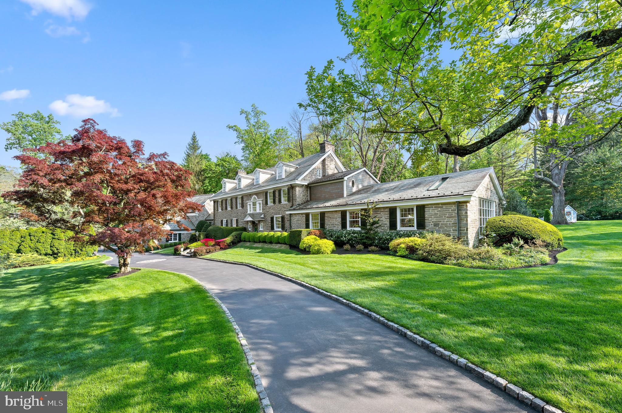Welcome to 221 South Aberdeen Avenue, a hidden gem quietly nestled on two breathtaking acres in the heart of South Wayne, where the TAXES HAVE BEEN REDUCED and are reasonable for an estate property of this grandeur!!This grand stone estate, constructed on all four sides, has remained one of Radnor Township’s best-kept secrets for nearly a century. Surrounded by lush, mature landscaping and offering unmatched privacy, it’s a rare opportunity to own a true legacy property within walking distance to downtown Wayne. Step inside to an expansive front-to-back Foyer capturing views of the backyard oasis with stunning fountain setting the tone for this grand dame. Flanked by a formal Living Room with a floor-to-ceiling bay window and spectacular fireplace, and a Dining Room with deep windowsills, the home is filled with natural light and timeless charm. A cozy Breakfast Room with its own fireplace connects seamlessly to the updated Kitchen featuring high-end appliances, custom cabinetry, and granite countertops, maintaining an open feel ideal to create gourmet meals for entertaining and everyday living. From the Kitchen, enter the glorious Sunroom with a hand-painted ceiling—an architectural jewel that connects the original home to the dramatic Great Room addition. With soaring ceilings, a custom hand-carved bar, and stained glass windows that fill the space with color and warmth, the Great Room is the ultimate entertainer’s dream. French doors open to a large deck that overlooks the expansive grounds, providing seamless indoor-outdoor flow. Off the Great Room is a private Office and Full Bathroom, making this area ideal for a guest suite, in-law accommodations, or a secluded work-from-home space. Whether hosting a garden party or enjoying a quiet morning coffee, the outdoor spaces offer unparalleled peace and privacy. Upstairs, the gracious Second-Floor landing features a beautiful arched window and window seat that add charm and character. The luxurious Primary Suite is a true retreat, offering His and Her Bathrooms and an incredible walk-in closet with exposed stone walls. Three additional Bedrooms and Two Full Baths provide ample space for family and guests. A well-positioned Laundry Room sits just off the back staircase, which offers direct access to the kitchen, making daily living effortless. The Third Floor features Two more Ensuite Bedrooms, perfect for extended family, guests, an au pair, or older children seeking their own space. These Upper-Level Rooms continue the home’s tradition of gracious scale, classic details, and exceptional versatility. Completing the home is an oversized 5-car garage—a rare and highly sought-after feature on the Main Line—paired with a convenient Mudroom area that keeps daily comings and goings beautifully organized. Behind the scenes, all major systems have been updated and are state-of-the-art, ensuring maximum comfort, efficiency, and peace of mind. The home has been meticulously maintained, a reflection of thoughtful ownership and timeless quality. The Lower Level offers yet another extraordinary feature: a custom walk-in, temperature-controlled Wine Cellar —perfect for collectors and entertainers alike. From its soaring ceilings and hand-carved woodwork to its tropical indoor pool and private outdoor entertaining spaces, 221 South Aberdeen Ave is truly one-of-a-kind. With its rare combination of architectural integrity, modern functionality, and walkability to everything Wayne has to offer, this home presents an opportunity that only comes along once in a generation!!