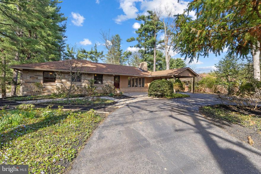 Charming stone and brick-accented ranch-style residence offering 4 bedrooms, 2.5 bathrooms, and 3,253 finished square feet, complete with a 1-car carport in the sought-after Glen Brook community. Lovingly maintained by the original owner, the home is introduced by a private circular driveway surrounded by lush landscaping, meandering stone pathways, and a welcoming front patio—creating a picturesque and inviting approach. // Inside, hardwood floors flow throughout the main level, connecting the open-concept formal living and dining rooms. The living room is filled with natural light from five bow windows and anchored by a striking double-sided wood-burning fireplace, adding warmth and character. // The kitchen is thoughtfully designed with black stainless steel appliances, Corian countertops, recessed lighting, a two-tiered center island, custom cabinetry, and ceramic tile flooring. Just beyond, the family room offers expansive picture windows and doors leading to the deck, along with built-ins including a desk area, a brick accent wall, and the opposite side of the shared fireplace—creating a seamless and inviting gathering space. // Hardwood flooring continues into three main-level bedrooms, including the spacious owner’s suite with a walk-in closet and a beautifully updated en suite bath (2020). One secondary bedroom features a convenient stackable laundry (2023) tucked within the closet, while another is privately situated toward the rear of the home. A second full bathroom completes the main level. // The walk-out lower level expands the living space with a large, open recreation room featuring plush carpeting, a wood stove, built-in cabinetry, and access to a glass-enclosed porch. This level also includes a fourth bedroom, an additional laundry area with patio access, a powder room, and a dedicated storage/workshop space. Additional updates include an E-max tankless water heater (2020) and a heat pump (2025). // Outdoor living is equally impressive, highlighted by an elevated deck and a stunning glass-enclosed porch with panoramic slate-glass views, a cathedral ceiling, and a hot tub—perfect for year-round enjoyment. The space opens to a beautifully hardscaped patio and a lush, tree-lined backyard with a storage shed, offering both privacy and tranquility.