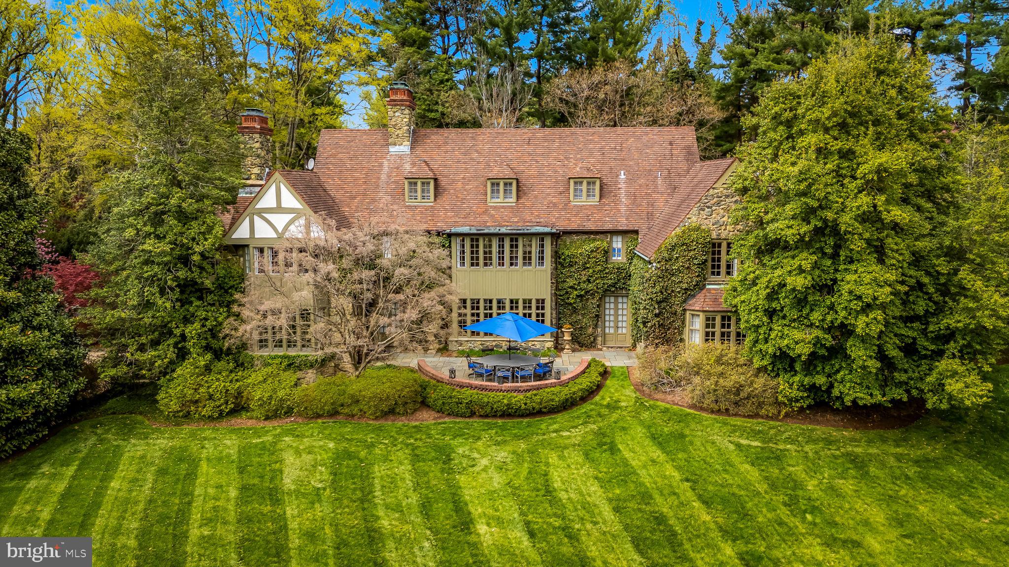 Welcome to this distinguished Baltimore estate, a residence of exceptional grace and grandeur designed by Palmer and Lamdin, as it awaits its next chapter. 102 Cotswold Road is an architectural treasure—a 1932 English Tudor Estate, set on 2.5 private acres in the highly desirable Homeland /Roland Park corridor. This nearly 9,000-square-foot stone manor offers an unmatched blend of historic charm, modern functionality, and estate-caliber grounds located in one of Baltimore’s most storied neighborhoods of Homeland. The home’s exterior evokes old-world elegance, with its hand-hewn stonework, layered tile roof, and leaded glass windows. A long, private drive leads to the front entrance, framed by mature trees and lush, manicured landscaping. Step inside to discover interiors that have been lovingly maintained and thoughtfully updated. Original intricate millwork, arched doorways, ironwork details, and 9’ ceilings reflect the craftsmanship of a bygone era. Designed for both gracious entertaining and comfortable daily living, the floor plan offers expansive rooms, a chef’s kitchen, a music room, cozy studies, sun-filled solariums, and intimate family spaces. The first level is also home to the grand primary suite, inclusive of dual renovated marble bathrooms with heated floors, multiple custom closets, and a gorgeous dressing room. Upstairs, multiple bedroom suites with renovated marble baths provide privacy and flexibility. The second level also offers an original sleeping porch that has been enclosed to house a bonus office room, plus a hallway office with built-in bookcases, and breathtaking views from every window. The third floor houses an expansive fanciful children’s playroom, full bathroom, and wonderful storage areas. Outdoors, the estate’s sweeping lawns, stone terraces, and park-like gardens create a private sanctuary right in the heart of town. Perfectly positioned near Baltimore’s top private schools, cultural institutions, restaurants and boutique shopping, this one-of-a-kind property is truly a rare offering—ideal for the discerning buyer seeking heritage, grandeur, space, and tranquility.