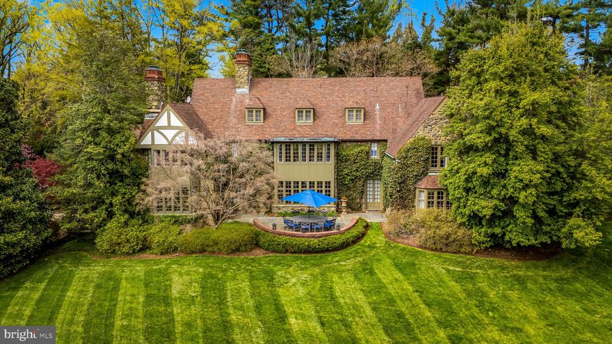Welcome to this distinguished Baltimore estate, a residence of exceptional grace and grandeur designed by Palmer and Lamdin, as it awaits its next chapter. 102 Cotswold Road is an architectural treasure—a 1932 English Tudor Estate, set on 2.5 private acres in the highly desirable Homeland /Roland Park corridor. This nearly 9,000-square-foot stone manor offers an unmatched blend of historic charm, modern functionality, and estate-caliber grounds located in one of Baltimore’s most storied neighborhoods of Homeland.  The home’s exterior evokes old-world elegance, with its hand-hewn stonework, layered tile roof, and leaded glass windows. A long, private drive leads to the front entrance, framed by mature trees and lush, manicured landscaping. Step inside to discover interiors that have been lovingly maintained and thoughtfully updated. Original intricate millwork, arched doorways, ironwork details, and 9’ ceilings reflect the craftsmanship of a bygone era.  Designed for both gracious entertaining and comfortable daily living, the floor plan offers expansive rooms, a chef’s kitchen, a music room, cozy studies, sun-filled solariums, and intimate family spaces. The first level is also home to the grand primary suite, inclusive of dual renovated marble bathrooms with heated floors, multiple custom closets, and a gorgeous dressing room. Upstairs, multiple bedroom suites with renovated marble baths provide privacy and flexibility. The second level also offers an original sleeping porch that has been enclosed to house a bonus office room, plus a hallway office with built-in bookcases, and breathtaking views from every window. The third floor houses an expansive fanciful children’s playroom, full bathroom, and wonderful storage areas.  Outdoors, the estate’s sweeping lawns, stone terraces, and park-like gardens create a private sanctuary right in the heart of town. Perfectly positioned near Baltimore’s top private schools, cultural institutions, restaurants and boutique shopping, this one-of-a-kind property is truly a rare offering—ideal for the discerning buyer seeking heritage, grandeur, space, and tranquility.