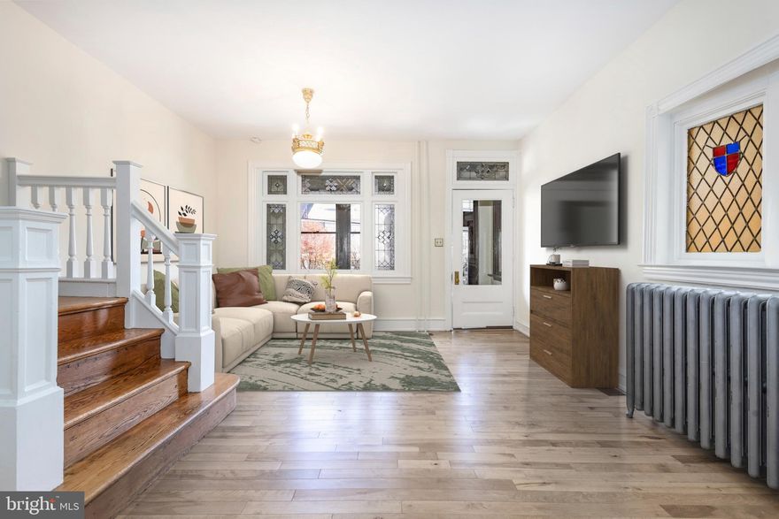 Welcome to this exceptional 5 bedroom, 2.5 bath end-of-row home, with a GARAGE, in the heart of historic East Falls; one of Northwest Philadelphia’s most walkable, bikeable, and community-forward neighborhoods. Lovingly and meticulously restored by its current owners, this home radiates warmth, character, and craftsmanship. Every room reflects their commitment to preserving original details while elevating the home for today’s modern lifestyle. Enter through the heated, window-lined front porch and step into the sun-filled living room with original cathedral glass and stained-glass windows, lofty ceilings, a stunning staircase, hardwood flooring, and a beautiful original light fixture. The generous dining room is perfect for everyday meals and memorable gatherings and features a built-in butler’s cabinet and a stylish powder room with pocket door. A fully renovated eat-in kitchen is a true showstopper: custom quarter-sawn solid oak cabinetry, leathered finish granite countertops, a wide island with seating for four, and the centerpiece - a beautifully restored Chambers stove complete with built-in warmer and broiler/griddle, vented to the exterior. Glass doors open to a private patio ideal for relaxing, grilling, or playing. An airy sunroom with underfloor heating, two skylights, and additional access to the backyard and side entrance, creates seamless indoor-outdoor flow. A handy back staircase leads directly from the kitchen to the second floor. The second floor features 3 bedrooms, including a spacious front room which was used as a family room, but is also perfect as a large second-floor primary. A pristine original hall bath with stained-glass window and a thoughtfully designed laundry room offer everyday convenience. The laundry room incorporates clever built-ins, closet space, and the home’s original porcelain sink hutch - charming and functional. On the third floor you’ll find two additional bedrooms and a newly added full bath. The rear bedroom could serve as a walk-in closet, office, or private retreat, creating an ideal third-floor primary suite. The unfinished basement provides excellent storage and includes direct access to the garage—making parking simple and secure. Notable upgrades include: updated electrical system (no knob and tube); two zone central AC, Anderson Renewal windows, fresh neutral paint, and an energy-efficient tankless water heater. Living in East Falls, you will enjoy the Saturday farmer’s market, many community events, super local restaurants, a community theater and live music at The Fallser Club. AND, this home is 4-minutes from both the train station (17 minutes to Center City) and the Schuylkill River Trail - a biker, runner or walker’s dream! AND, an amazing sledding hill - fun for kids and adults! Easy access to I-76, and minutes to Manayunk, City Line Ave. and more! All photos with furniture have been digitally staged.