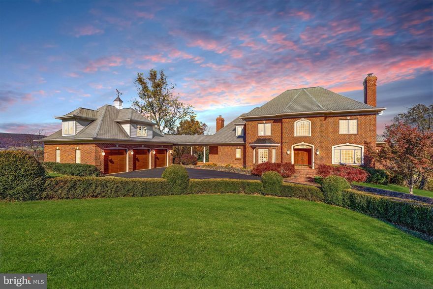 Experience resort-style living within Stoneleigh Country Club community in this French Provincial style, all-brick custom estate, perfectly positioned on one of the most beautiful lots in the area. Set on nearly 3 private acres 🌳 at the end of a quiet cul-de-sac, this exquisite well-built home welcomes you with a grand horseshoe driveway accented by vintage stone walls and mature landscaping. Blending timeless elegance with comfortable livability, this home offers 4,920 square feet throughout two levels, with breathtaking mountain and golf course views ⛰️⛳, a 3-car garage with an unfinished loft, a cupola with weathervane, a covered breezeway, and abundant storage throughout. Well-designed for both grand entertaining and multi-generational living, the residence features 5 bedrooms, 4 full baths, and 2 half baths, and includes two primary suites—one on the main level and one on the upper level.

Upon entry, a dramatic circular mahogany staircase and rich mahogany hardwood floors set a tone of warmth and sophistication. The formal dining room showcases a tray ceiling, bay window, and a well-appointed butler’s pantry with a barrel ceiling, cabinetry, wine rack, sink, and pocket doors. An inviting living room with fireplace provides flexible use, while the expansive great room impresses with a floor-to-ceiling stone fireplace, custom built-in bookshelves, and a wall of windows framing panoramic views of the Catoctin, Blue Ridge, and Sugarloaf mountains. Pocket doors allow for optional separation between the great room and the gourmet kitchen, which features cherry cabinetry with pull-out shelving, granite countertops, a center island, and a spacious eat-in area overlooking the picturesque setting. A secondary staircase provides convenient access to the upper level. Just off the kitchen, a Trex deck ☕🍷 offers the perfect spot for coffee at sunrise or wine at sunset. Another room adjoining the kitchen features a vaulted mahogany ceiling and gas fireplace, creating a cozy atmosphere. Also on the main level is a large laundry/mudroom with cabinetry and sink, two conveniently placed half baths—plus additional closets and built-in storage.

The main-level primary suite features mountain views, a walk-in closet, and a spa-inspired bath with double sinks, a soaking tub, and a walk-in shower. Upstairs, the luxurious primary suite offers a relaxing sitting area with a tray ceiling, a three-sided fireplace and built-in media cabinet, a large walk-in closet with wet bar, and access to another Trex deck 🌅. The en suite bath has dual sinks, a jetted soaking tub, and walk-in shower. Three additional bedrooms are located on the upper level—one with a private bath and two sharing a hall bath.

The unfinished walk-out lower level, with 10-foot ceilings, multiple windows, two bathroom rough-ins and exceptional storage capacity, provides an outstanding opportunity for future finished space. The unfinished loft above the garage also offers flexibility for additional storage, a workshop, or studio.

Outdoor living is a defining feature of this peaceful setting, with mature landscaping providing year-round color and privacy. It is perfectly suited for dining, entertaining, or simply enjoying the tranquil surroundings. Located within the Stoneleigh Country Club community ⛳, residents have access to a scenic championship golf course, clubhouse, tennis courts, and a swimming pool—all set amidst the natural beauty of western Loudoun County’s rolling countryside. This impressive location offers exceptional convenience—just 30 minutes to Dulles International Airport ✈️, approximately an hour to Washington, D.C., and nearby access to Route 7, local wineries 🍷, dining, and shopping. With low HOA dues of $75 per year and the benefit of public utilities (no well or septic), this one-of-a-kind estate offers the perfect blend of luxury, privacy, convenience, and lifestyle. Schedule your private tour today.