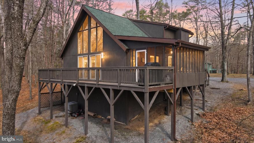 Popular chalet-style home in The Woods community situated on 1.9 wooded acres offering a private setting. This home features 3 bedrooms with the primary on the entry level, 2 full baths, and approximately 1,600 sq. ft. of living space.

The great room is highlighted by vaulted ceilings, a wall of windows, and two sliding glass doors that fill the space with natural light and wooded views.  A gas fireplace serves as the focal point, creating a comfortable and inviting gathering space. Kitchen includes granite countertops, stainless steel appliances, and breakfast bar.

Upstairs bathroom includes a skylight, adding natural light to the space.

Elevated deck and large screened porch offer outdoor living and entertaining space.

Recent updates include decking, gutters with guards, updated windows, roof, and water heater.

A Class B Membership is available for transfer, providing access to community amenities including indoor and outdoor pools, fitness center, and recreational facilities.