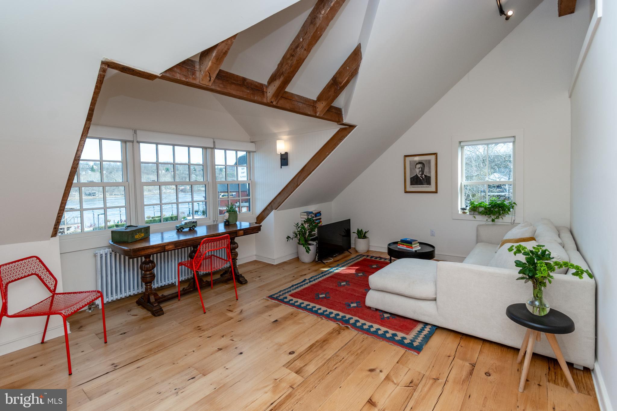 OFFERING ONE MONTH FREE FOR A SIGNED LEASE BY THE END OF AUGUST! Enjoy historic charm and modern luxury in this beautifully renovated light-filled 1-bedroom, 1-bath apartment in the heart of New Hope, PA. Featuring exposed wood beams, wood floors, and modern updates, this third-floor home offers stunning Delaware River views - and INCLUDES PRIVATE PARKING - a rare, in-town perk!
A bright living room offers the perfect space to relax or work from home while gazing at the River. The updated kitchen boasts white cabinetry, quartz counters, and stainless steel appliances, while the contemporary bathroom includes a walk-in shower and radiant heated floors. A full-sized washer and dryer add convenience, and custom lighting enhances the space.
Steps from Bucks County Playhouse, this prime location over Farley's Bookshop, offers renowned restaurants, boutique shops, art galleries, and the scenic river promenade and canal towpath. The New York Times recently named Bucks County a top destination, rivaling the Hamptons—now you can call it home! No smoking or pets. Also note, this is a third-floor walk-up. No elevator. *Photos reflect a previous tenant's furnishings.